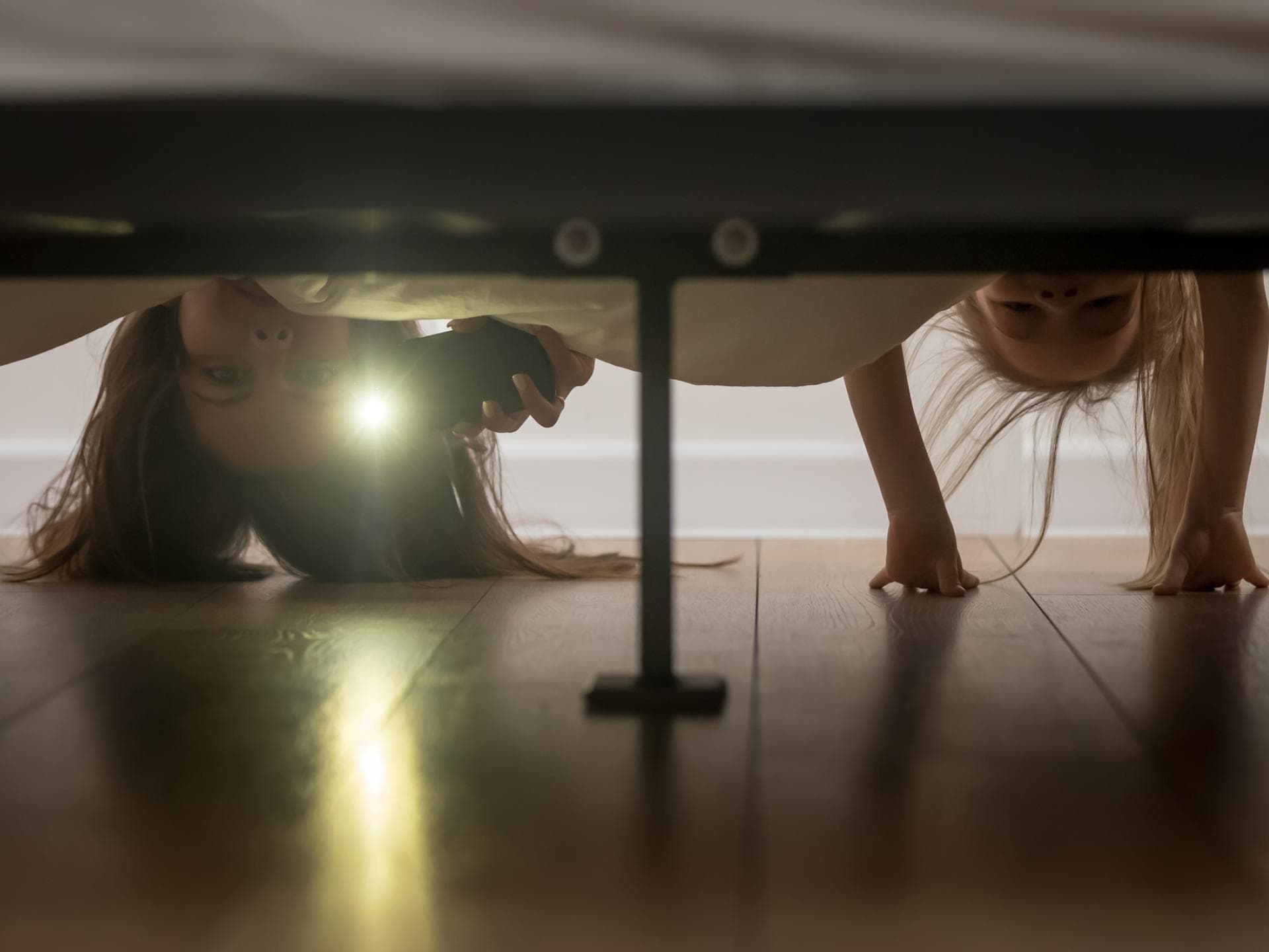 Mutter und Tochter schauen mit Taschenlampe unters Bett Mutter und Tochter schauen mit Taschenlampe unters Bett