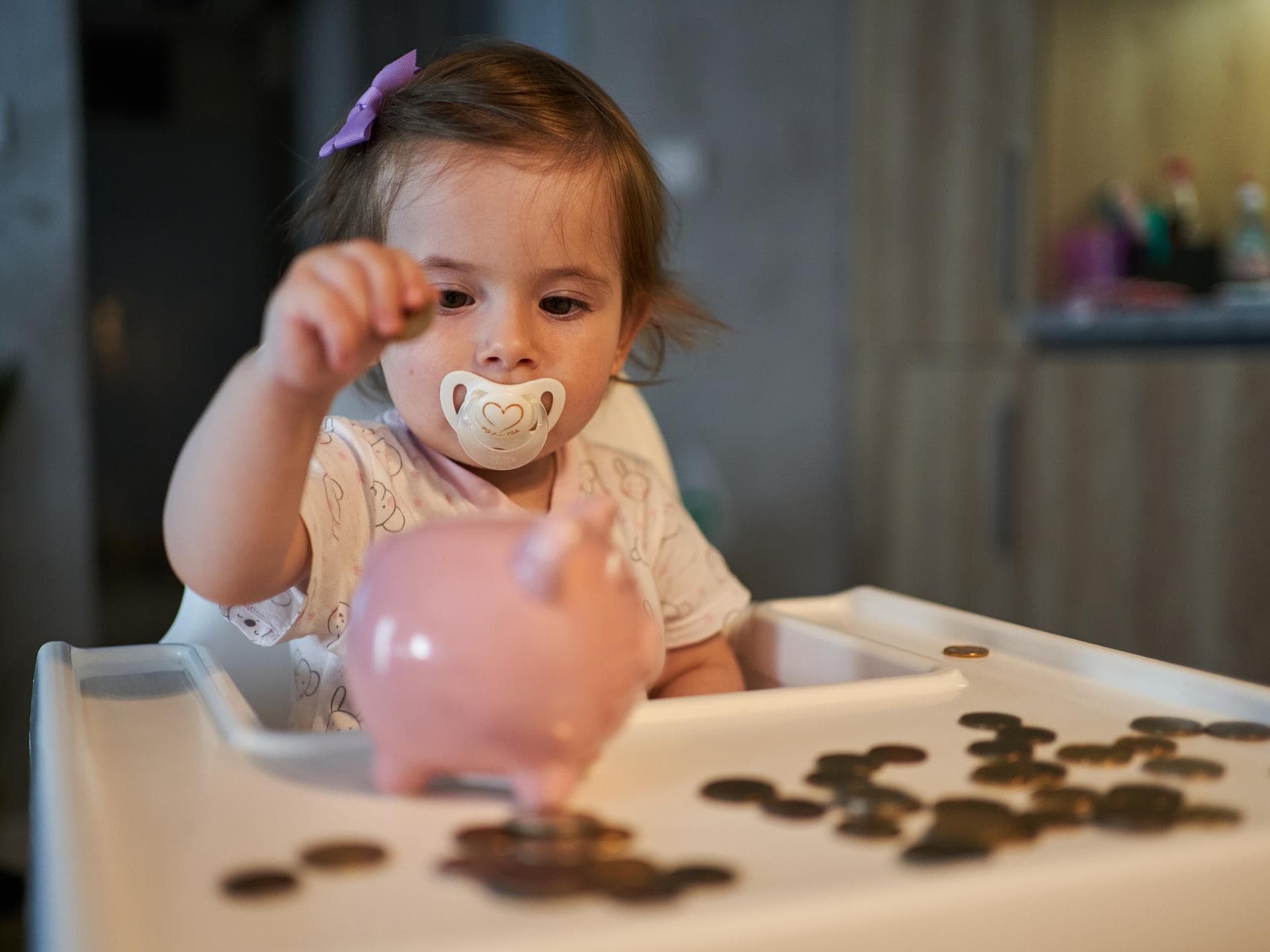 Kleinkind wirft Geld ins Sparschwein.