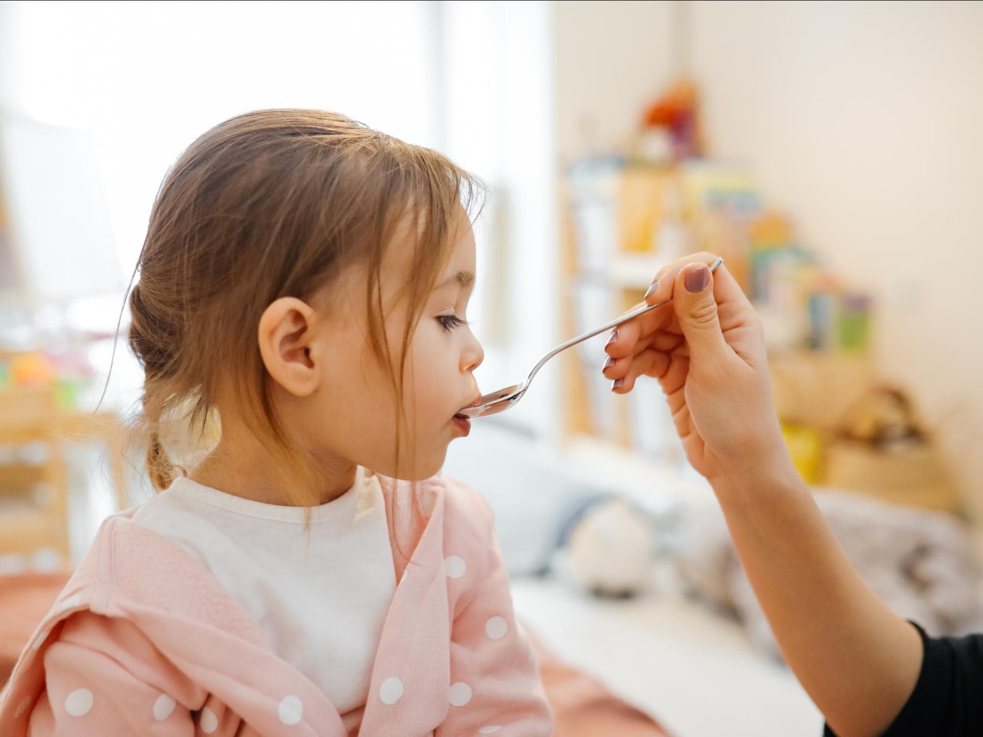Mädchen bekommt einen Löffel mit Medizin