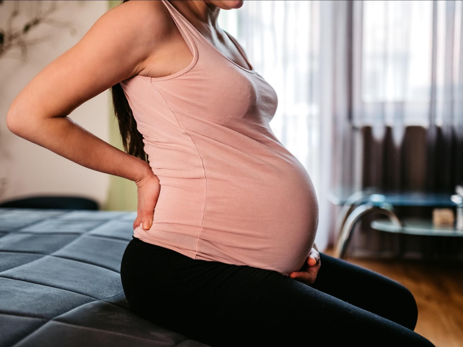 Hochschwangere Frau hält sich Bauch und Rücken Hochschwangere Frau hält sich Bauch und Rücken