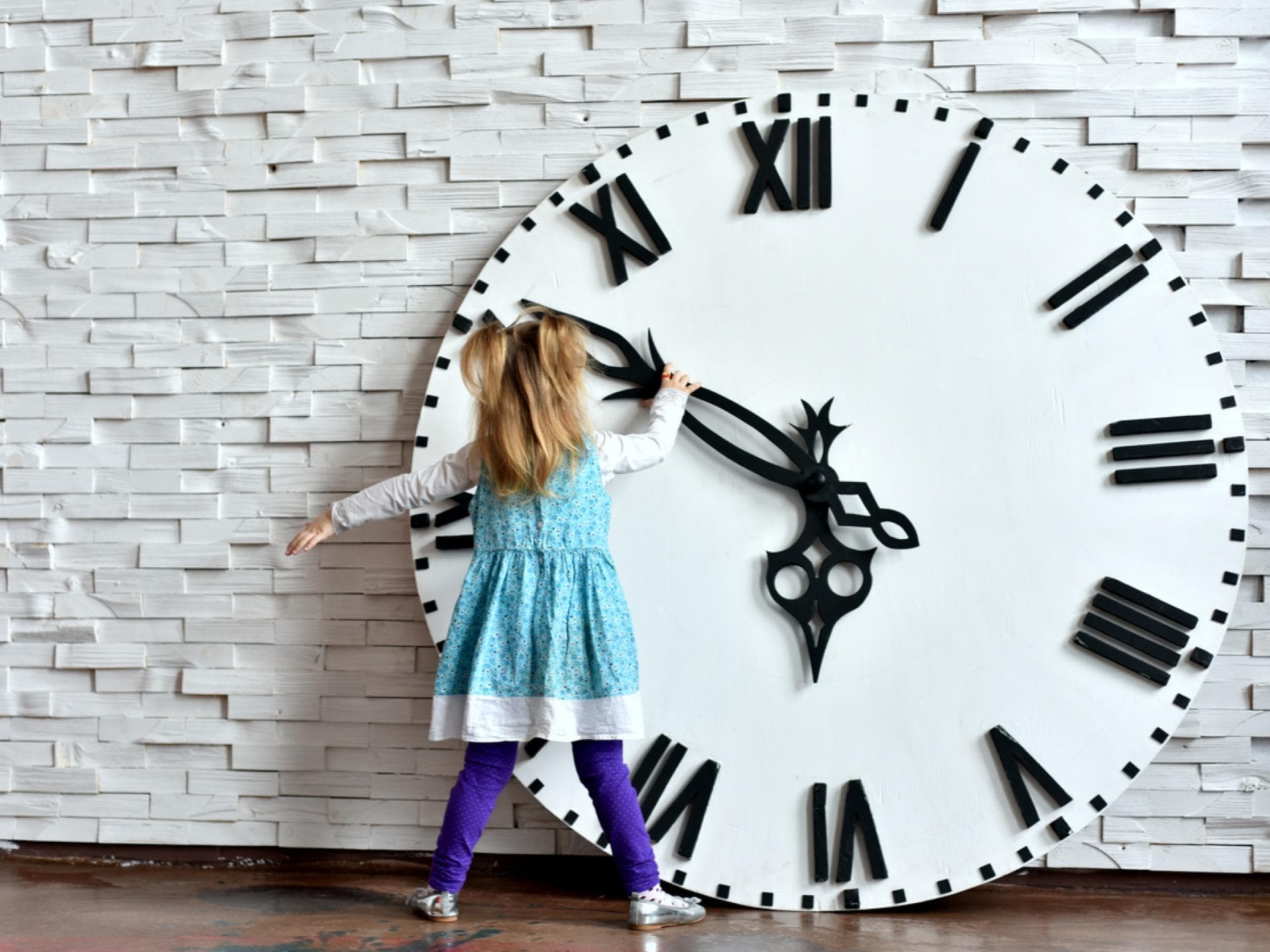 Kleines Mädchen steht vor riesiger Uhr