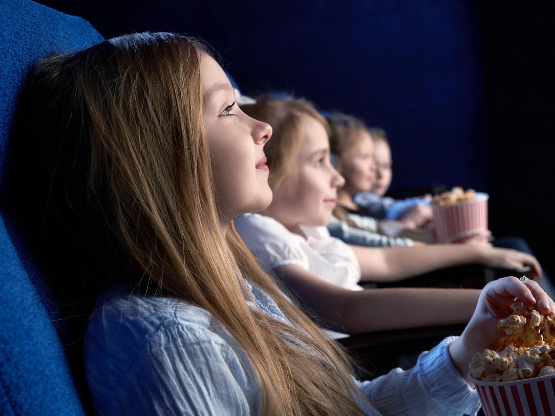 Junge Kinder sitzen im Kino und essen Popcorn. 