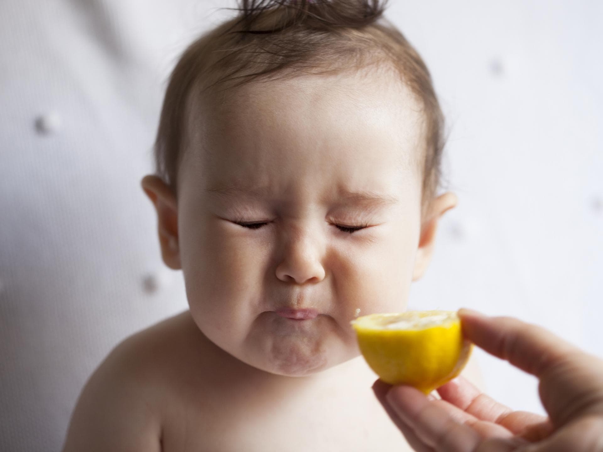 Ein kleines Baby isst eine Zitrone und verzieht das Gesicht. Ein kleines Baby isst eine Zitrone und verzieht das Gesicht.