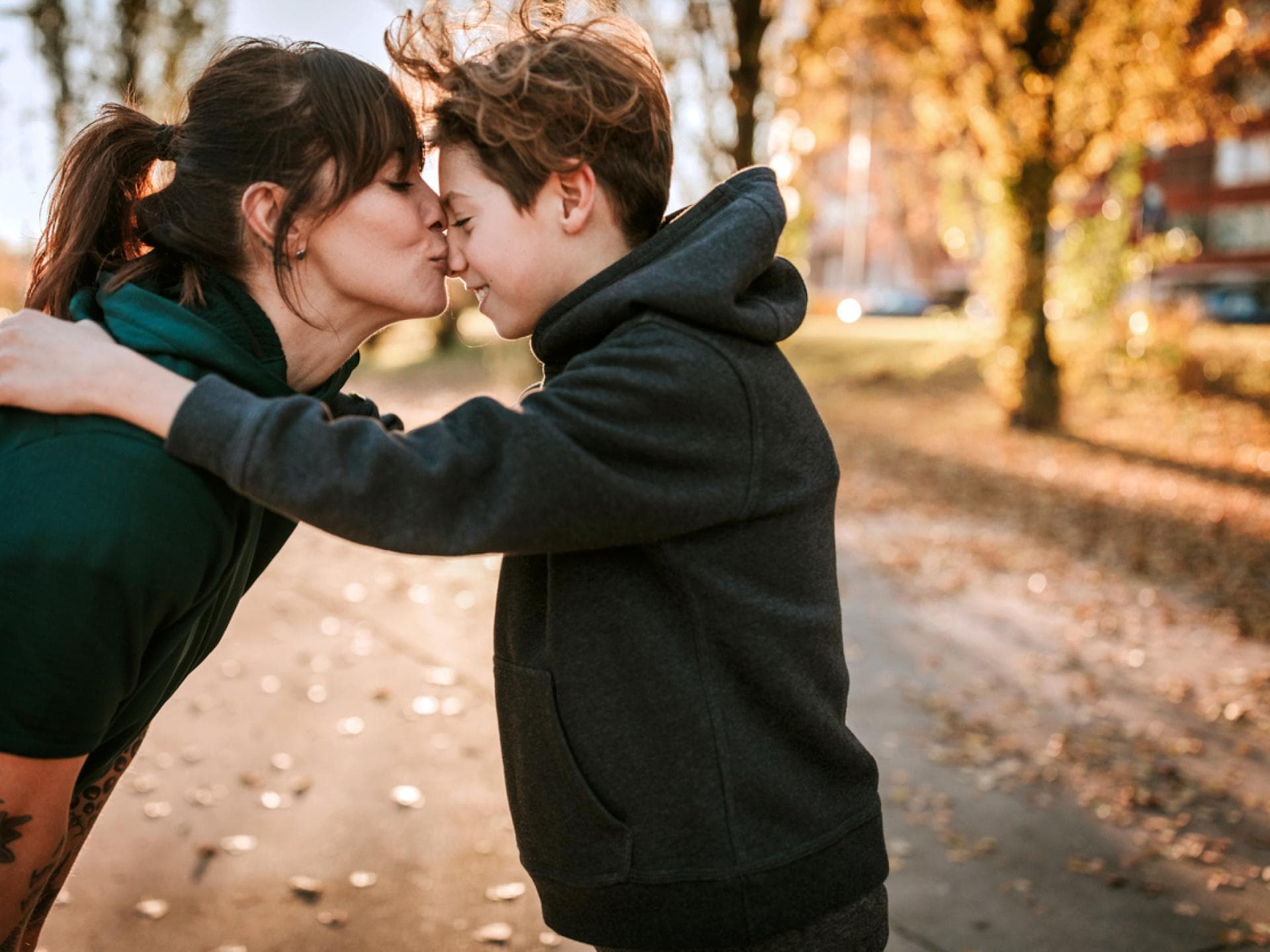 Eine Mutter küsst ihren Teenager-Jungen zärtlich auf die Nase. 