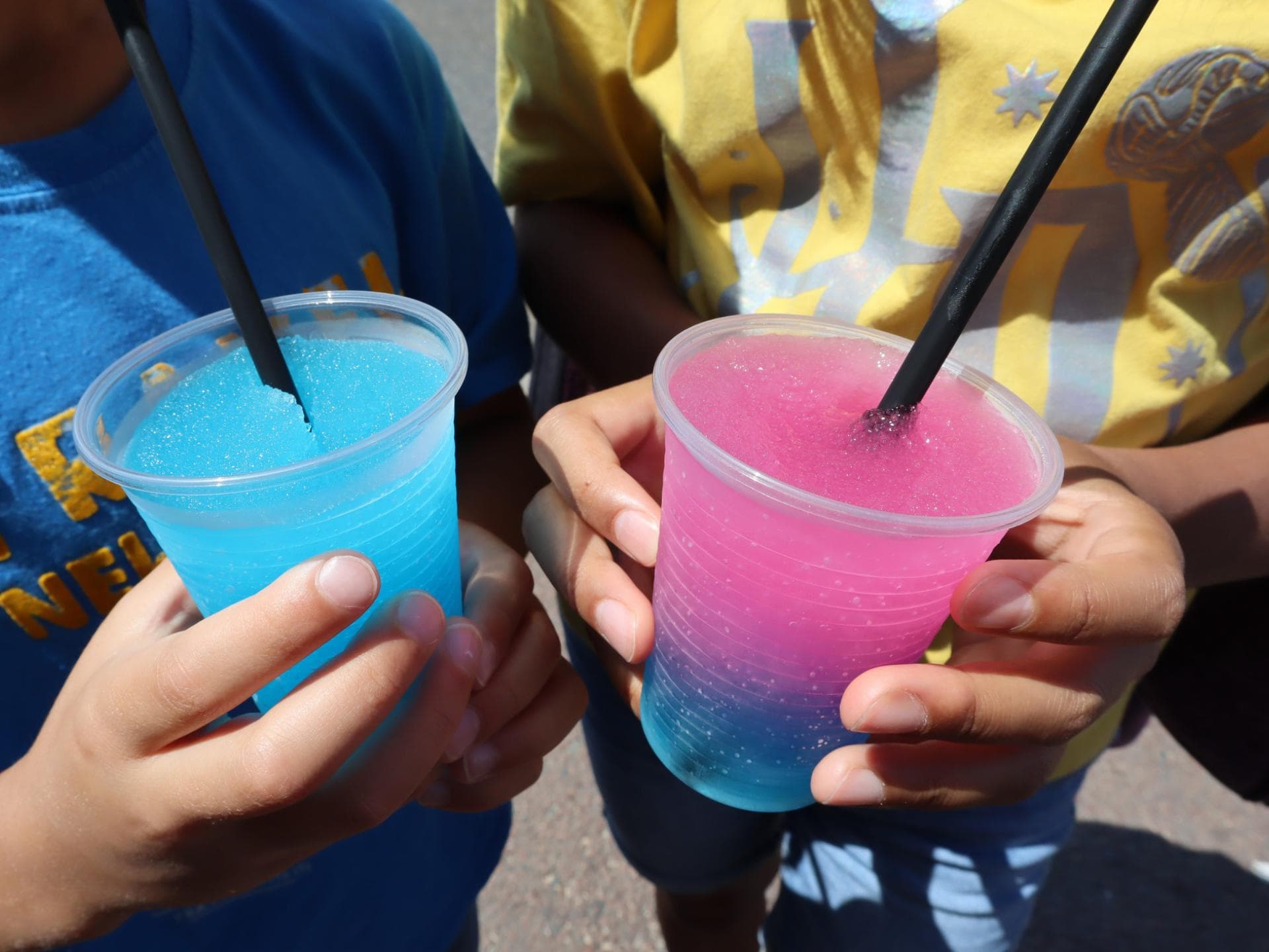 Zwei Kinder trinken rosa-blauen Slush. 