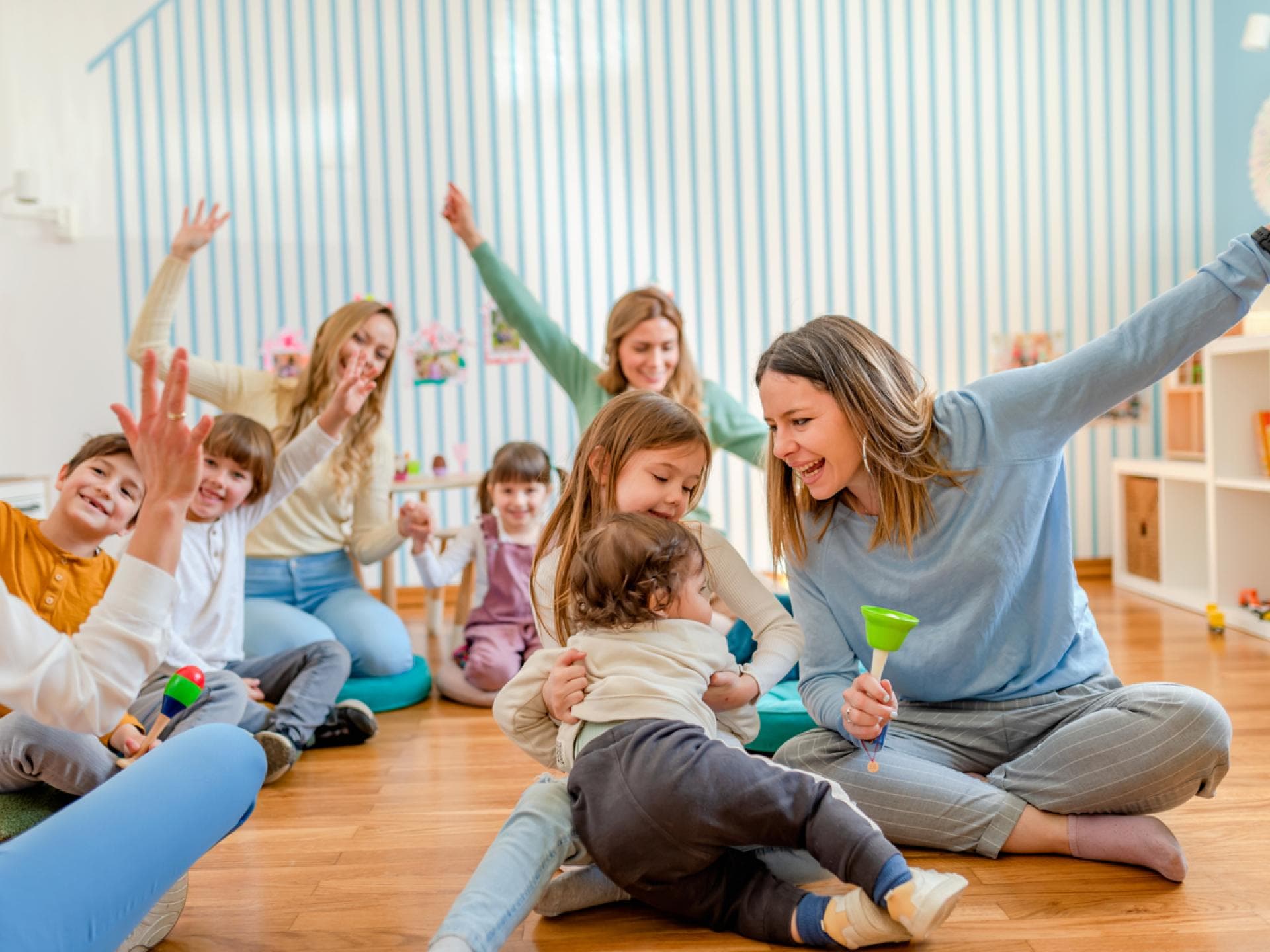Erzieherinnen spielen mit Kita-Kindern und haben gemeinsam Spaß.