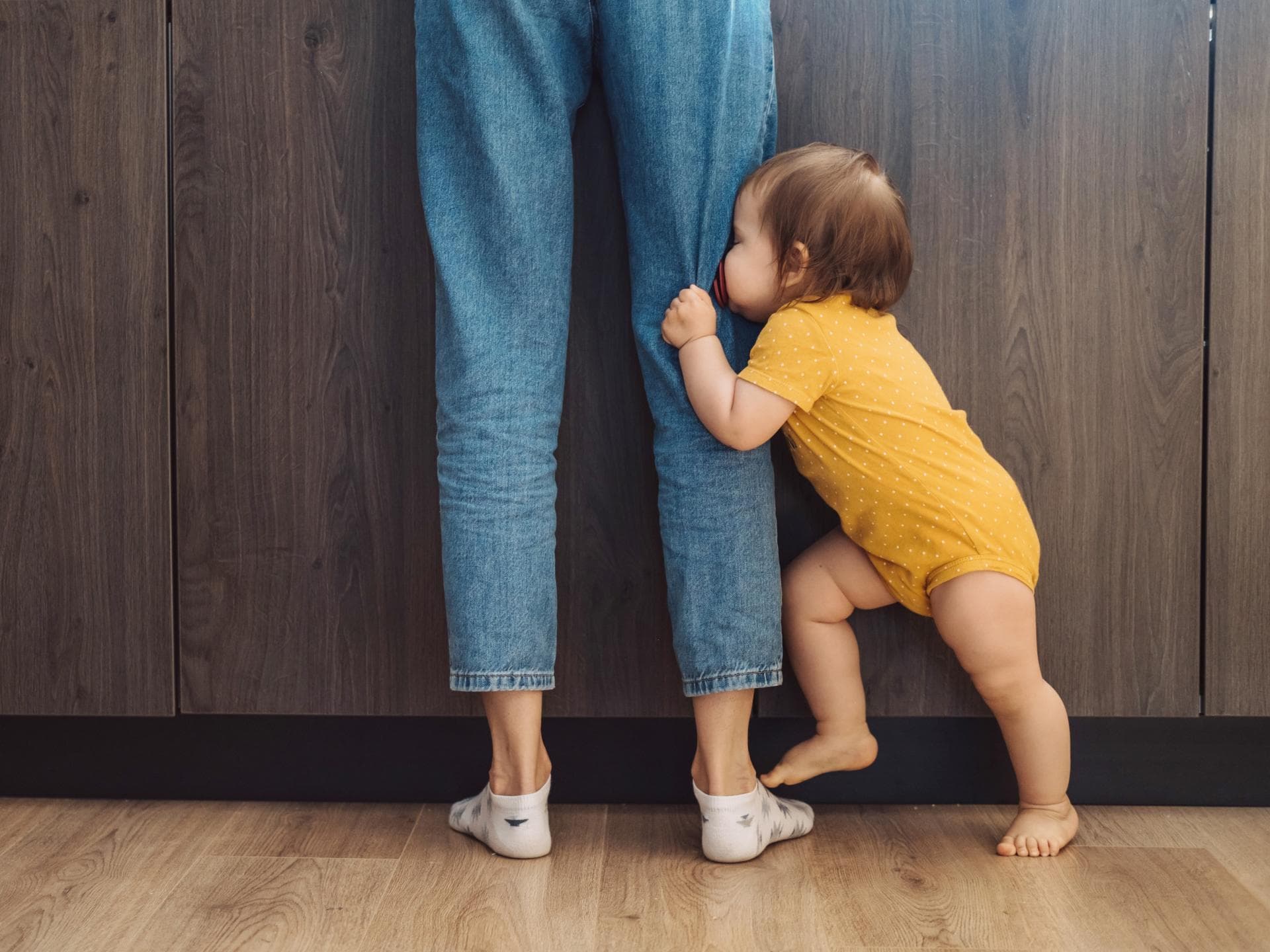 Baby, das sein Gesicht hinter den Beinen seiner Mutter versteckt. Baby, das sein Gesicht hinter den Beinen seiner Mutter versteckt.