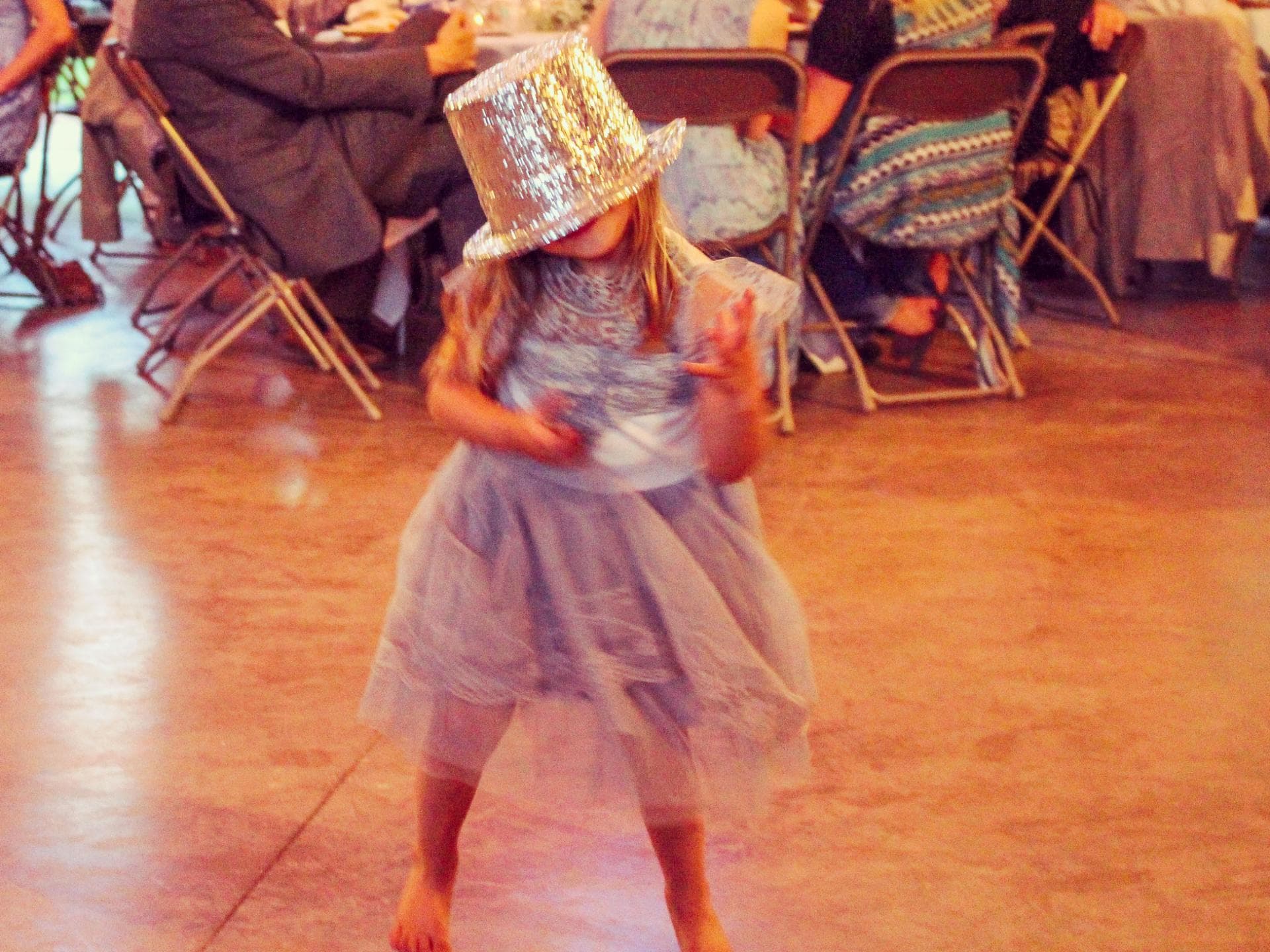 Kind mit Glitzerhut tanzt auf einer Hochzeit