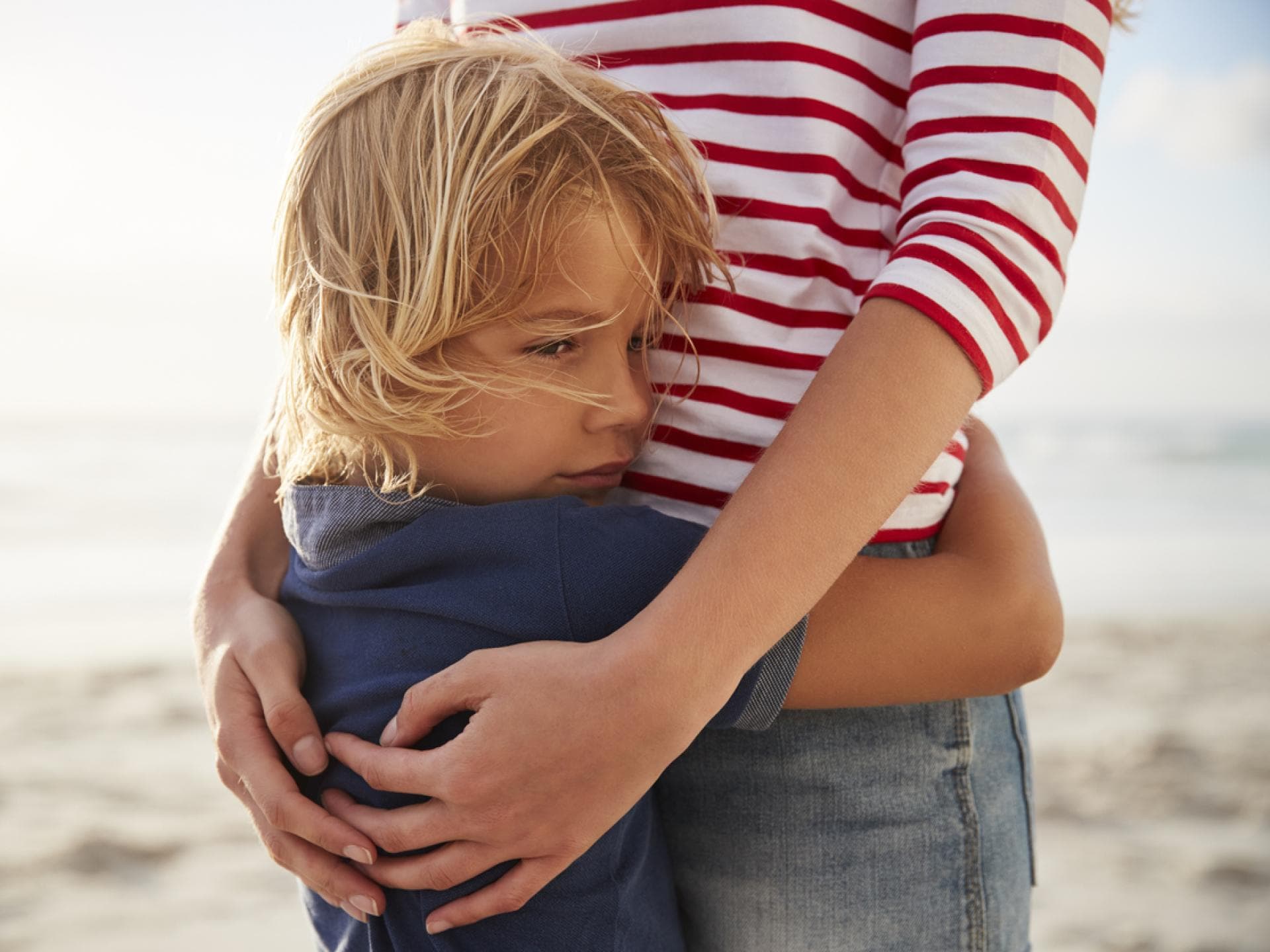 Mutter umarmt Sohn am Strand.