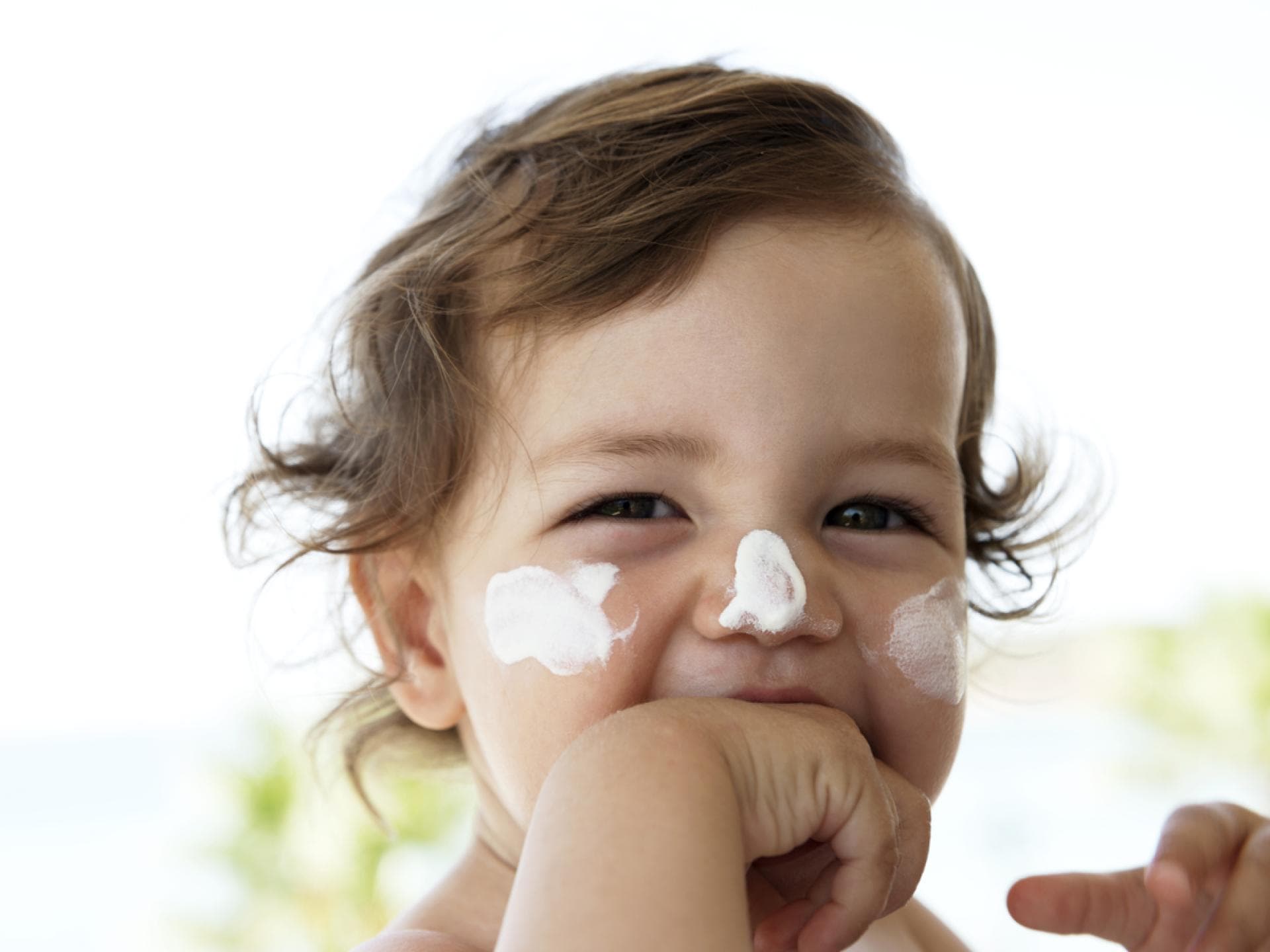 Kleines Kind mit Sonnencreme im Gesicht