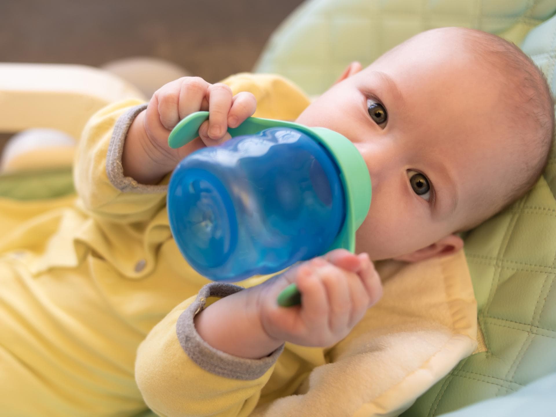Ein Baby trinkt an seinem besten Trinklernbecher