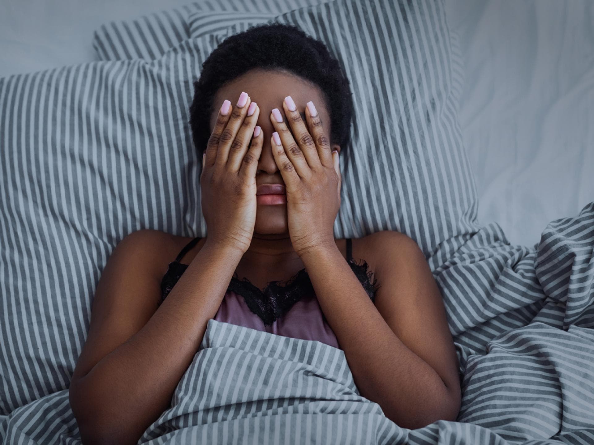 Eine Frau liegt mit Händen vor den Augen im Bett und kann nicht schlafen! Eine Frau liegt mit Händen vor den Augen im Bett und kann nicht schlafen!