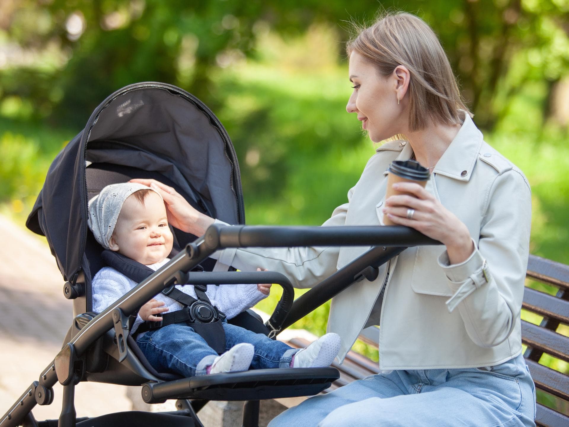 Eine Mutter streichelt ihr Baby im Kinderwagen über den Kopf. Eine Mutter streichelt ihr Baby im Kinderwagen über den Kopf.