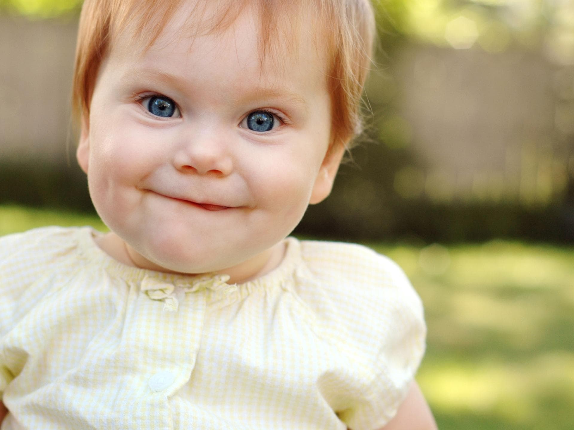 Ein Baby-Mädchen mit roten Haaren lächelt und freut sich über ihren englischen Mädchennamen. Ein Baby-Mädchen mit roten Haaren lächelt und freut sich über ihren englischen Mädchennamen.