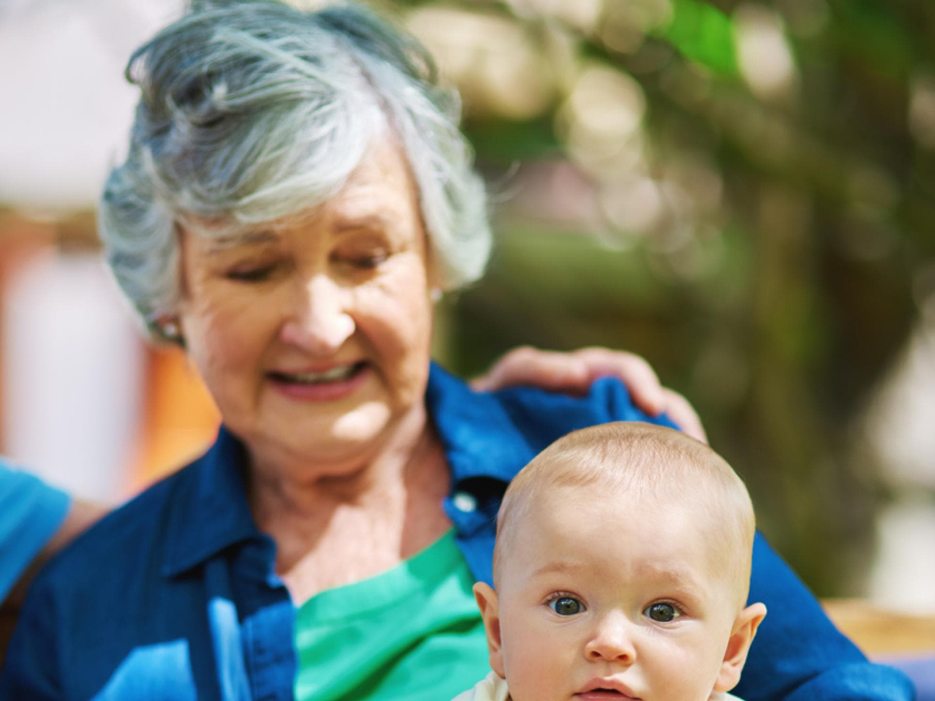 Baby sitzt bei Oma auf dem Schoss.