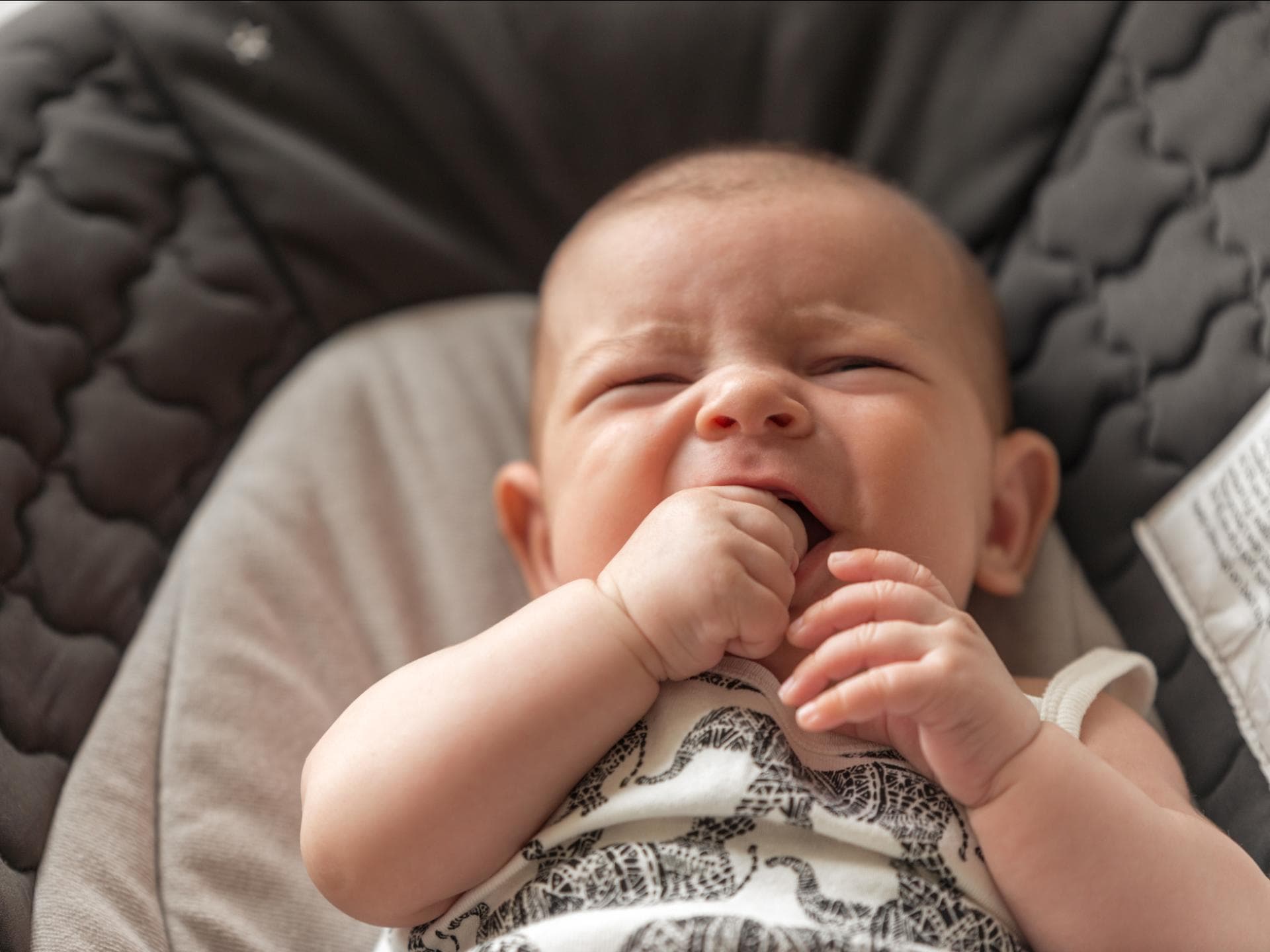 Quengeliges Baby kaut auf seiner Hand