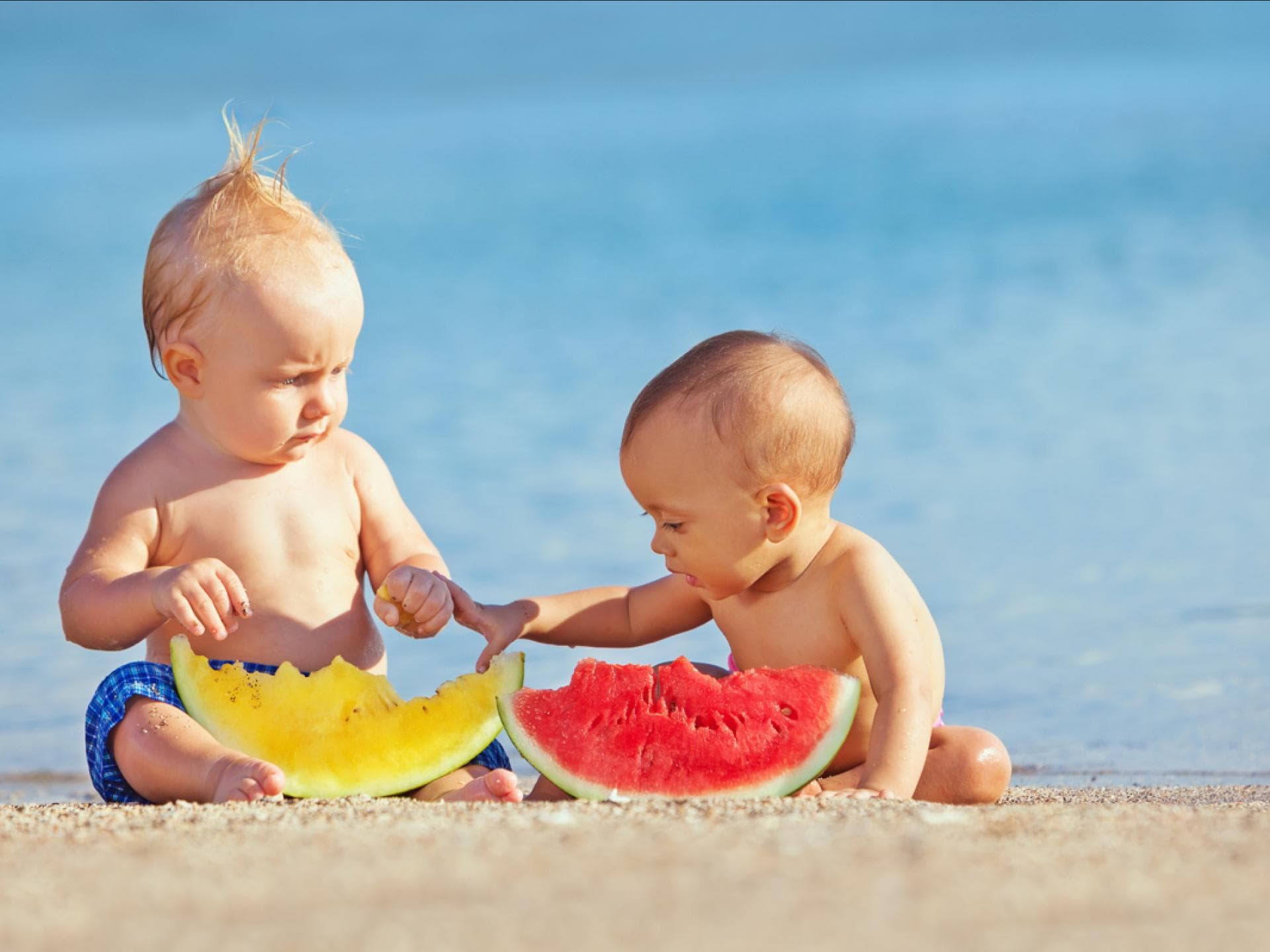 Zwei Babys essen am Strand Melone. Zwei Babys essen am Strand Melone.