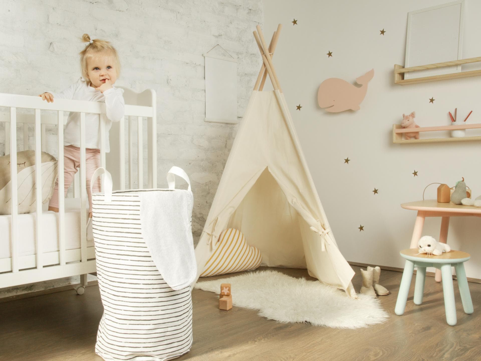 Ein kleines Mädchen steht in ihrem Kinderbett im Kinderzimmer.