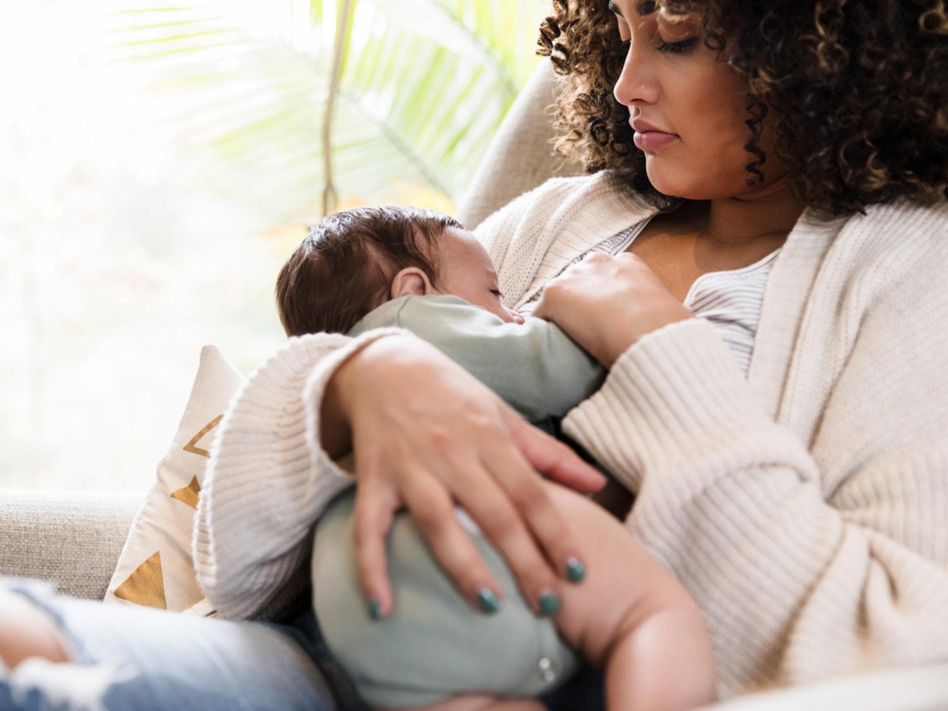 Junge Mutter stillt ihr Baby in einer ihrer liebsten Stillpositionen. Junge Mutter stillt ihr Baby in einer ihrer liebsten Stillpositionen.