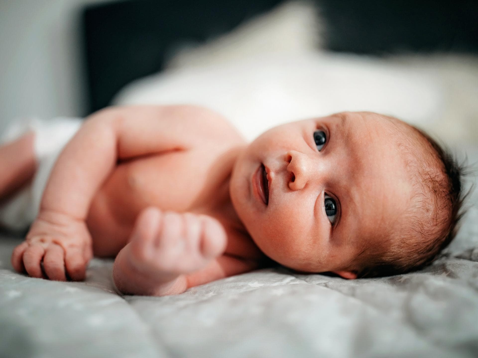 Taavi ist ein außergewöhnlicher Name für Jungen. Neugeborenes Baby liegt auf einer Decke.