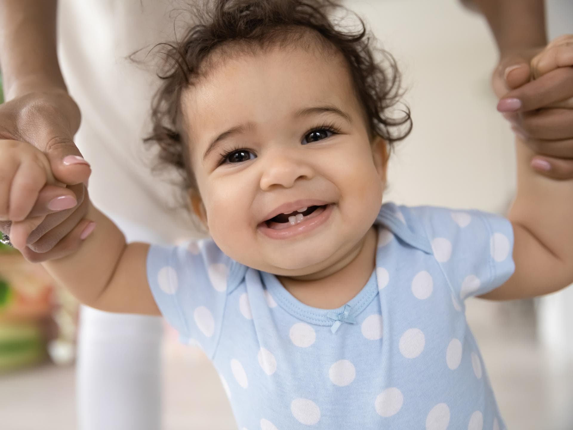 Ein kleines Mädchen läuft grinsend ihre ersten Schritte an der Hand der Mutter. Ein kleines Mädchen läuft grinsend ihre ersten Schritte an der Hand der Mutter.
