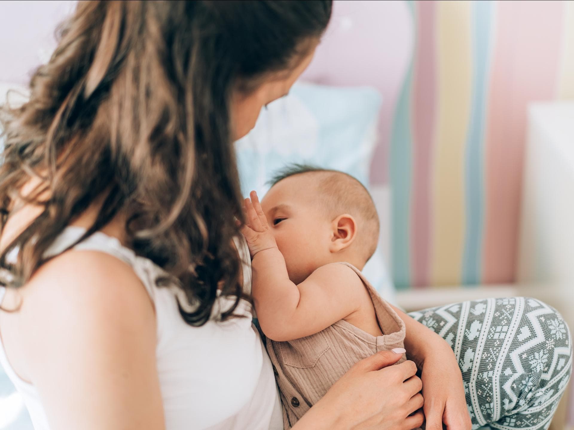 Eine Frau stillt im Sitzen ihr Baby.