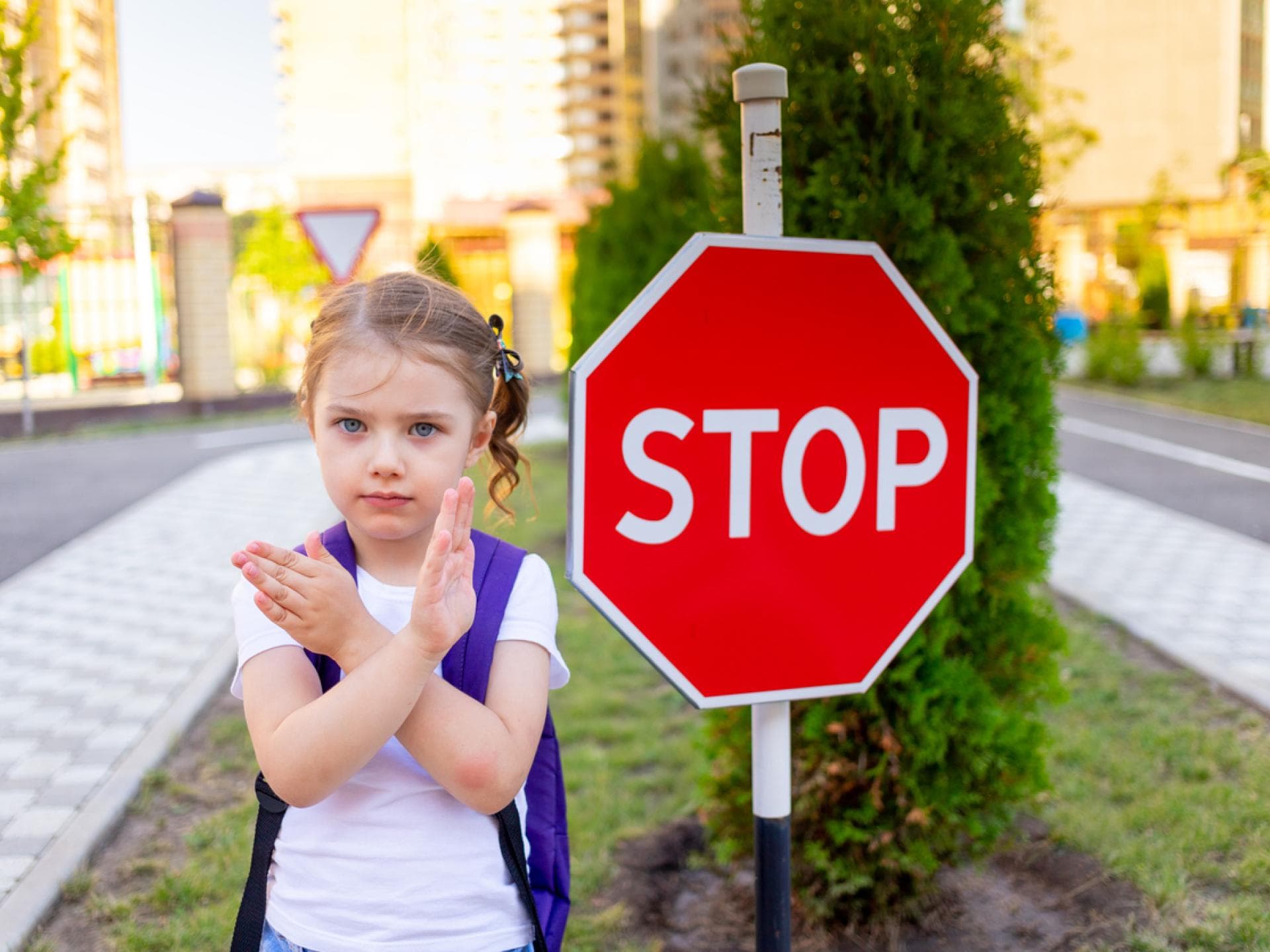 Grenzen ziehen: Kleines Schulmädchen sagt Nein an einem Stopp-Schild Grenzen ziehen: Kleines Schulmädchen sagt Nein an einem Stopp-Schild