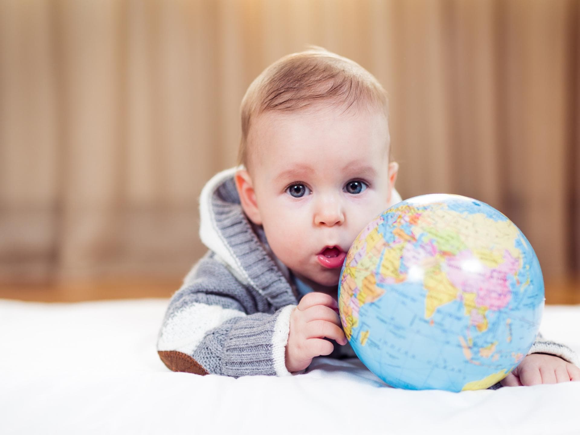 Baby-Junge liegt auf dem Boden mit einem Globus in der Hand. Baby-Junge liegt auf dem Boden mit einem Globus in der Hand.