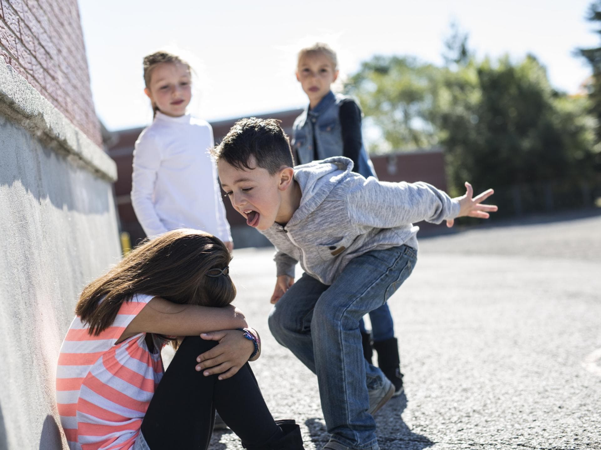 Mobbing an der Grundschule: Kinder ärgern ein kleines Mädchen auf dem Schulhof. Mobbing an der Grundschule: Kinder ärgern ein kleines Mädchen auf dem Schulhof.