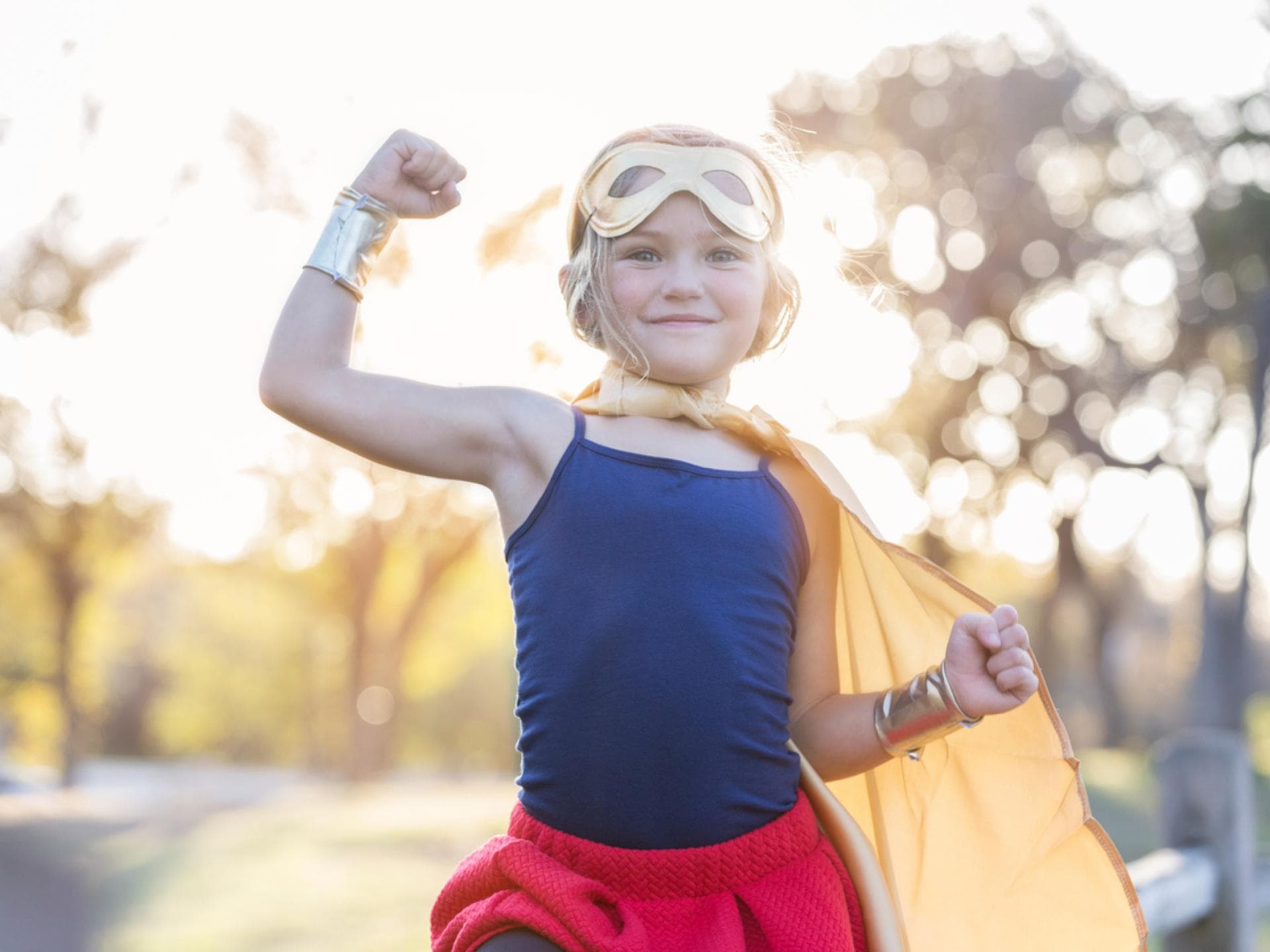 Kleines blondes Mädchen im Superhelden-Kostüm zeigt, wie stark sie ist. Kleines blondes Mädchen im Superhelden-Kostüm zeigt, wie stark sie ist.