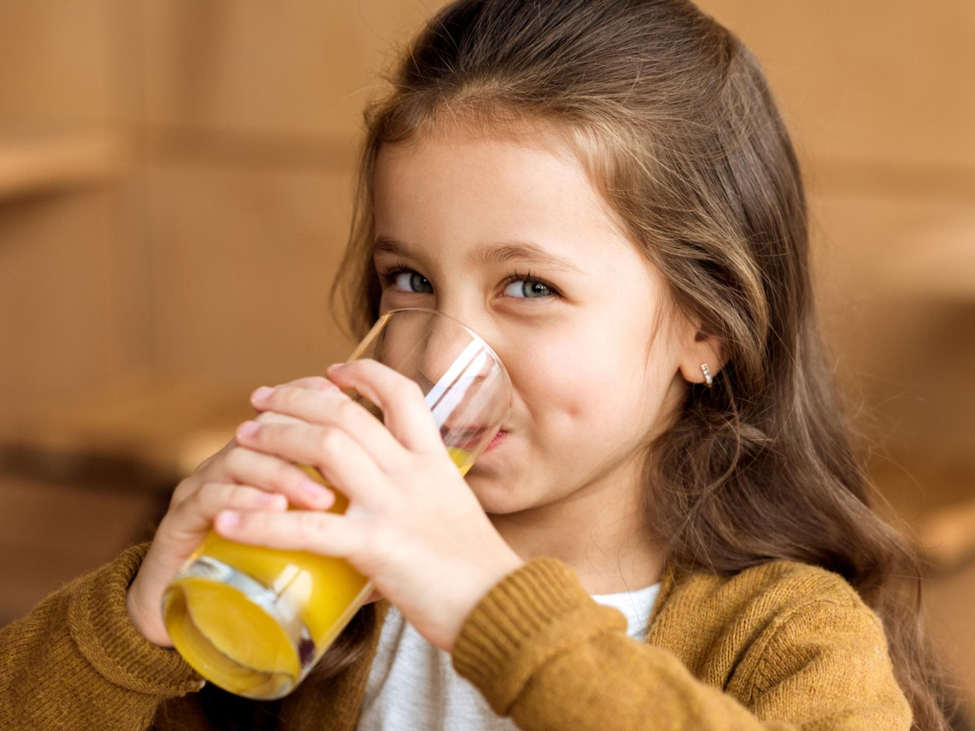 Lächelndes Mädchen trinkt ein Glas Orangensaft