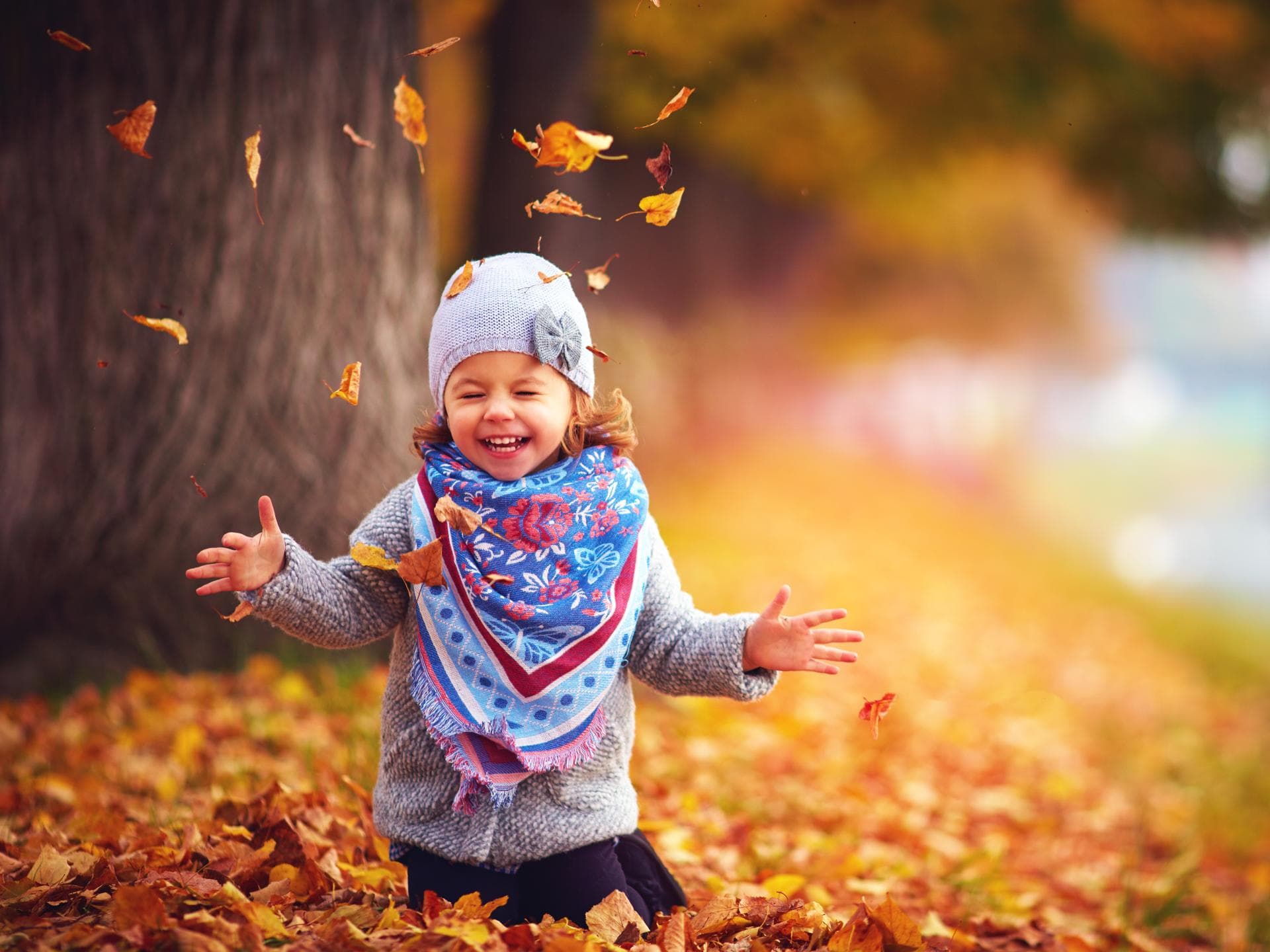 Ein Mädchen spielt im Herbstlaub.