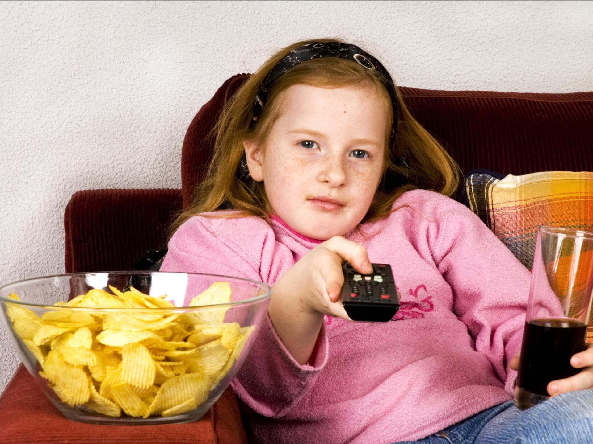 Mädchen mit Cola, Fernbedienung und Chips. Mädchen mit Cola, Fernbedienung und Chips.
