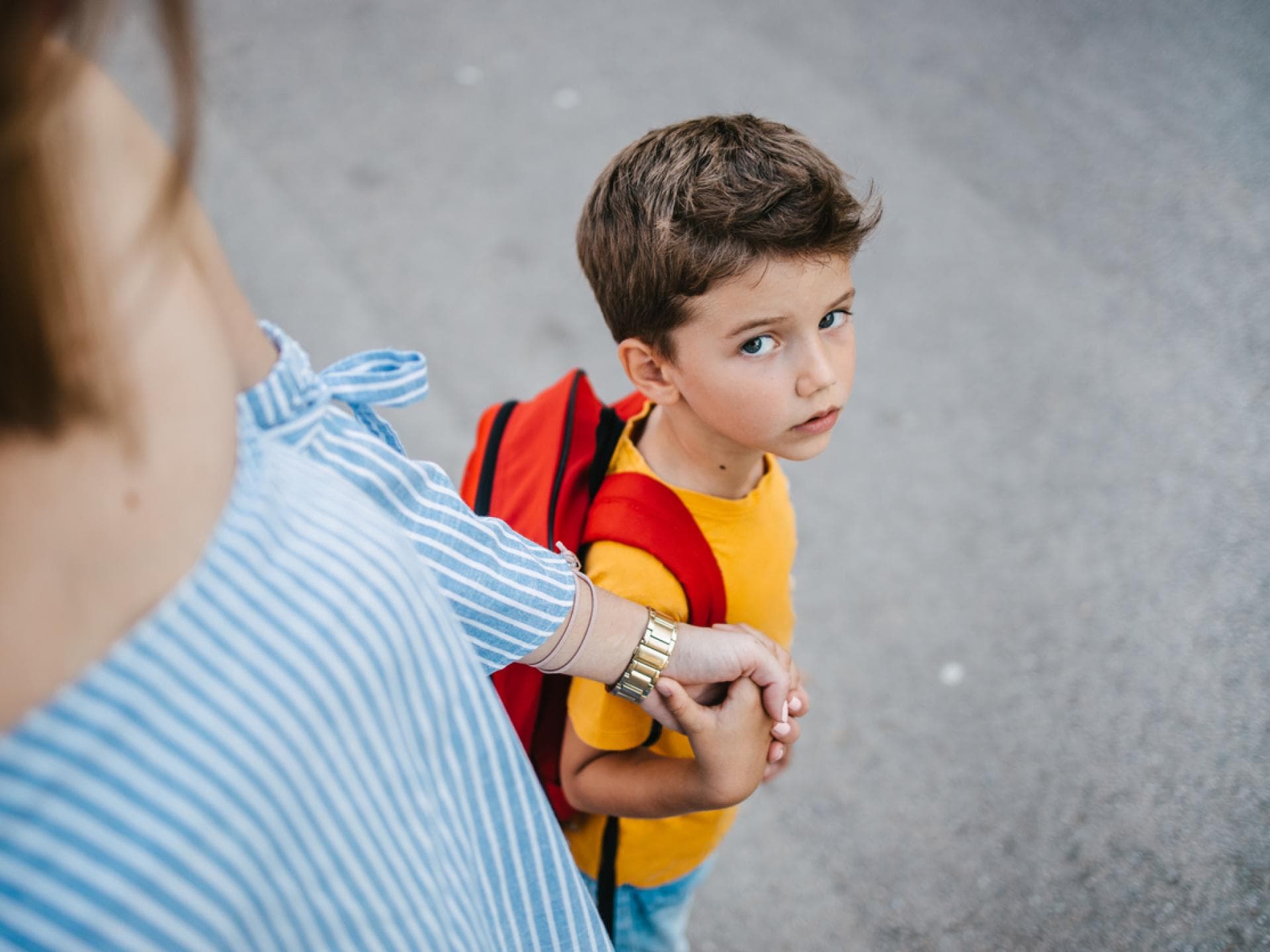 Viele Kinder wollen morgens nicht in die Kita. Mutter hält die Hand ihres Sohnes und bringt ihn zur Schule.