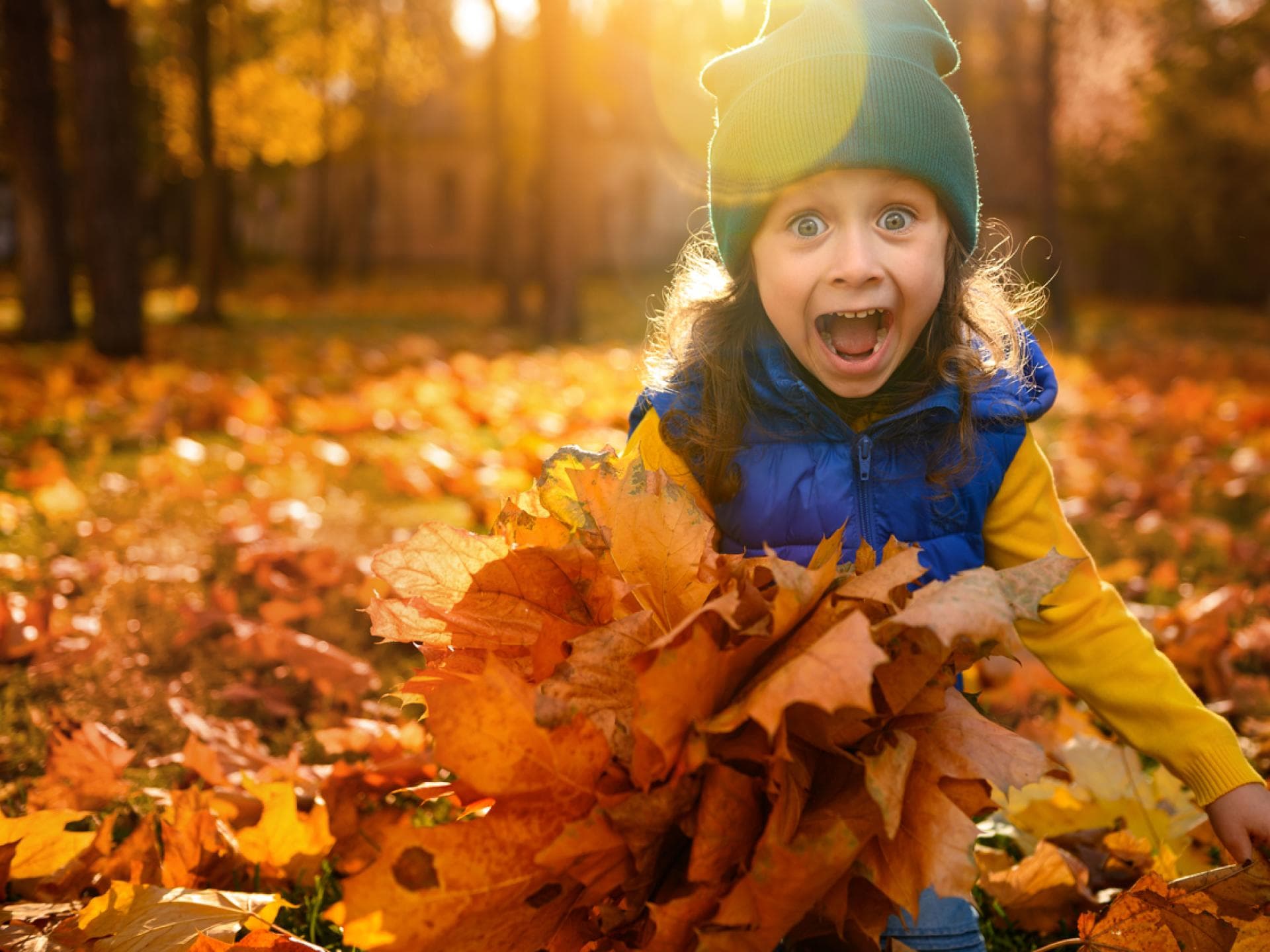 Viele Vornamen haben im Oktober Namenstag. Lachendes Mädchen spielt im Herbstlaub.