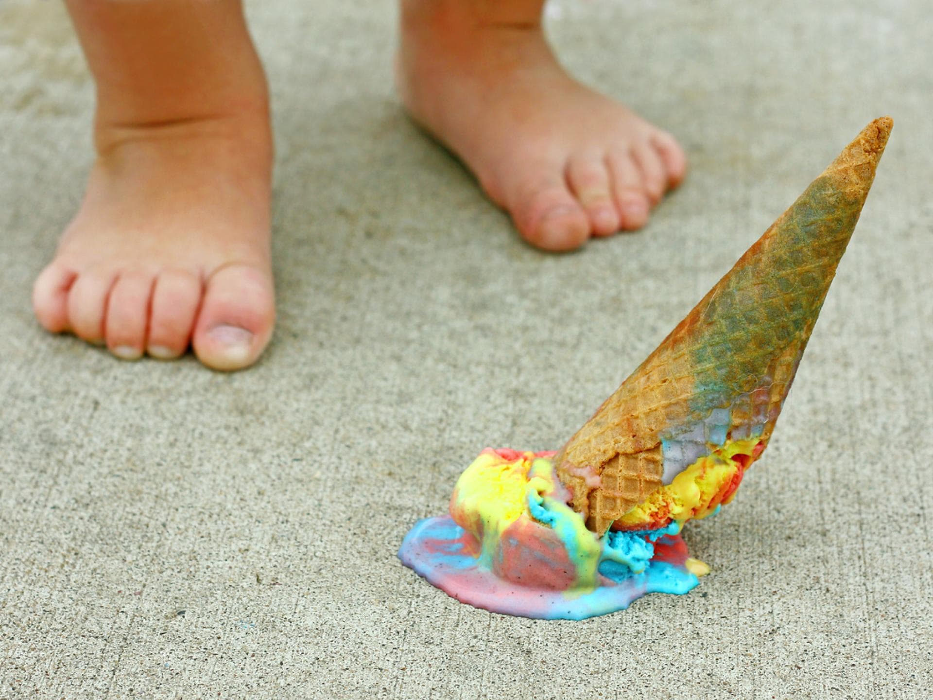 Nackte Kinderfüße, ein Eis liegt auf dem Boden