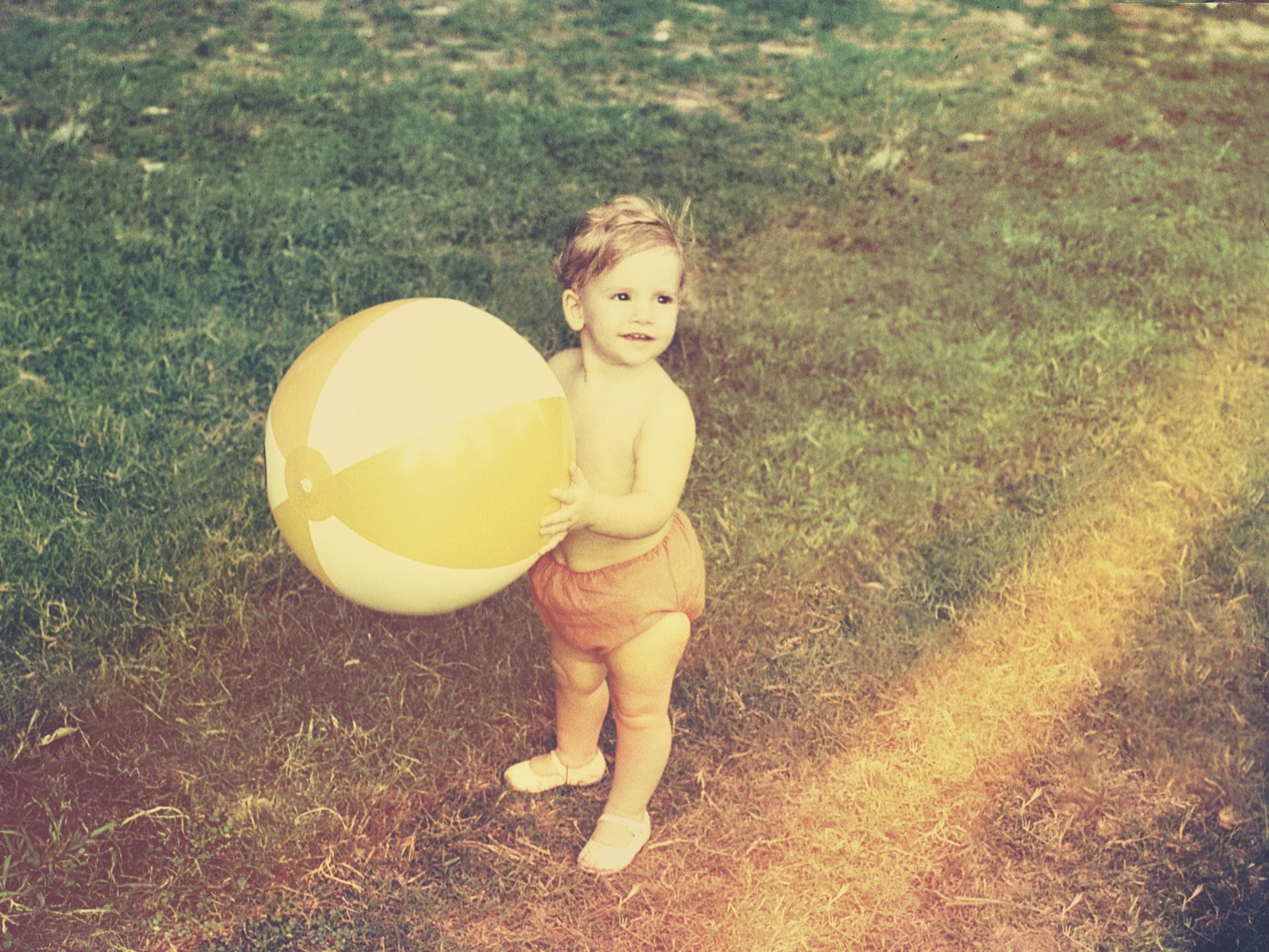 Kleinkind mit Wasserball im Garten