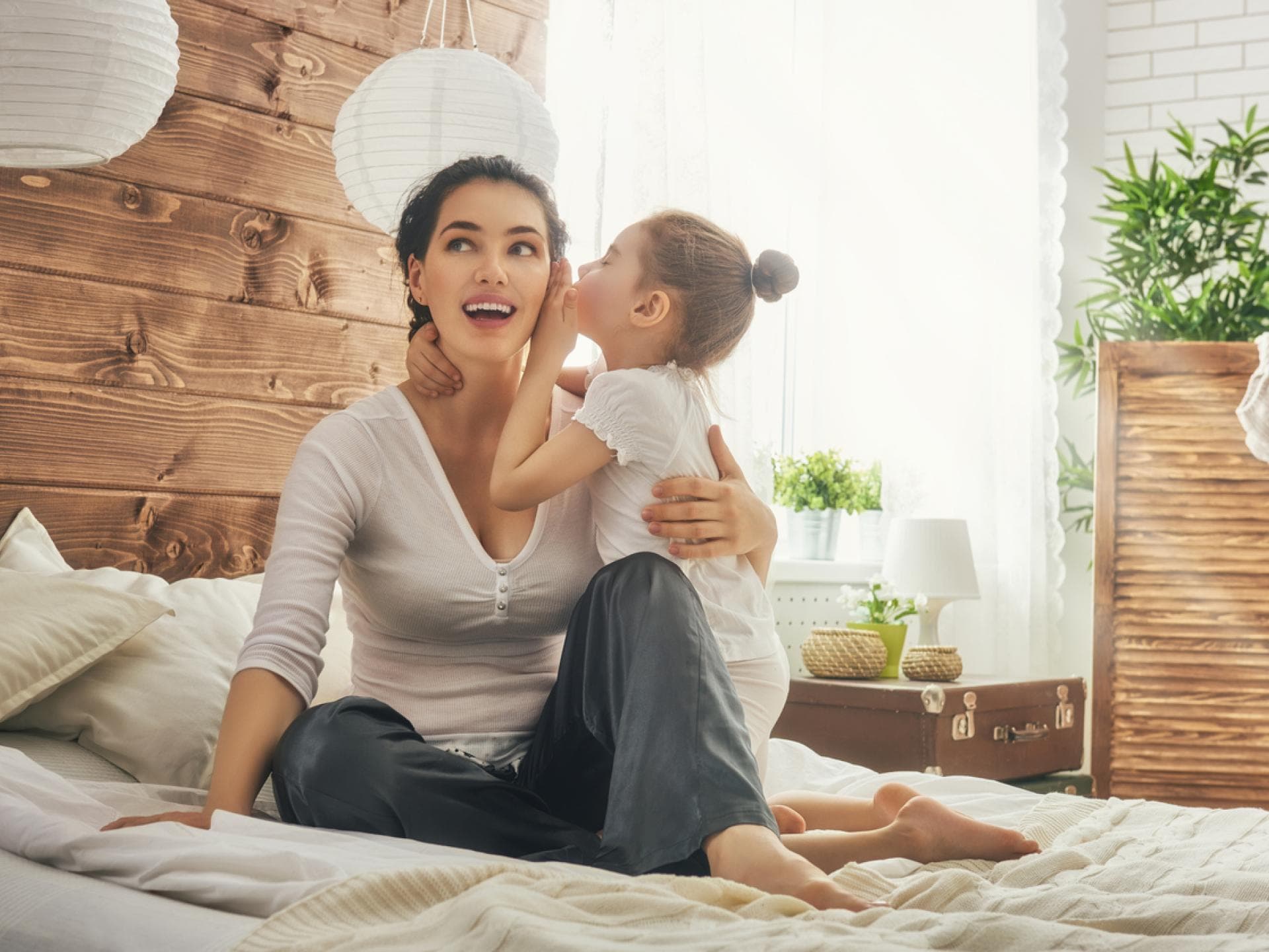 Mit ein paar Tricks lässt sich die Eltern-Kind-Bindung verbessern. Mädchen flüstert seiner Mama etwas ins Ohr.