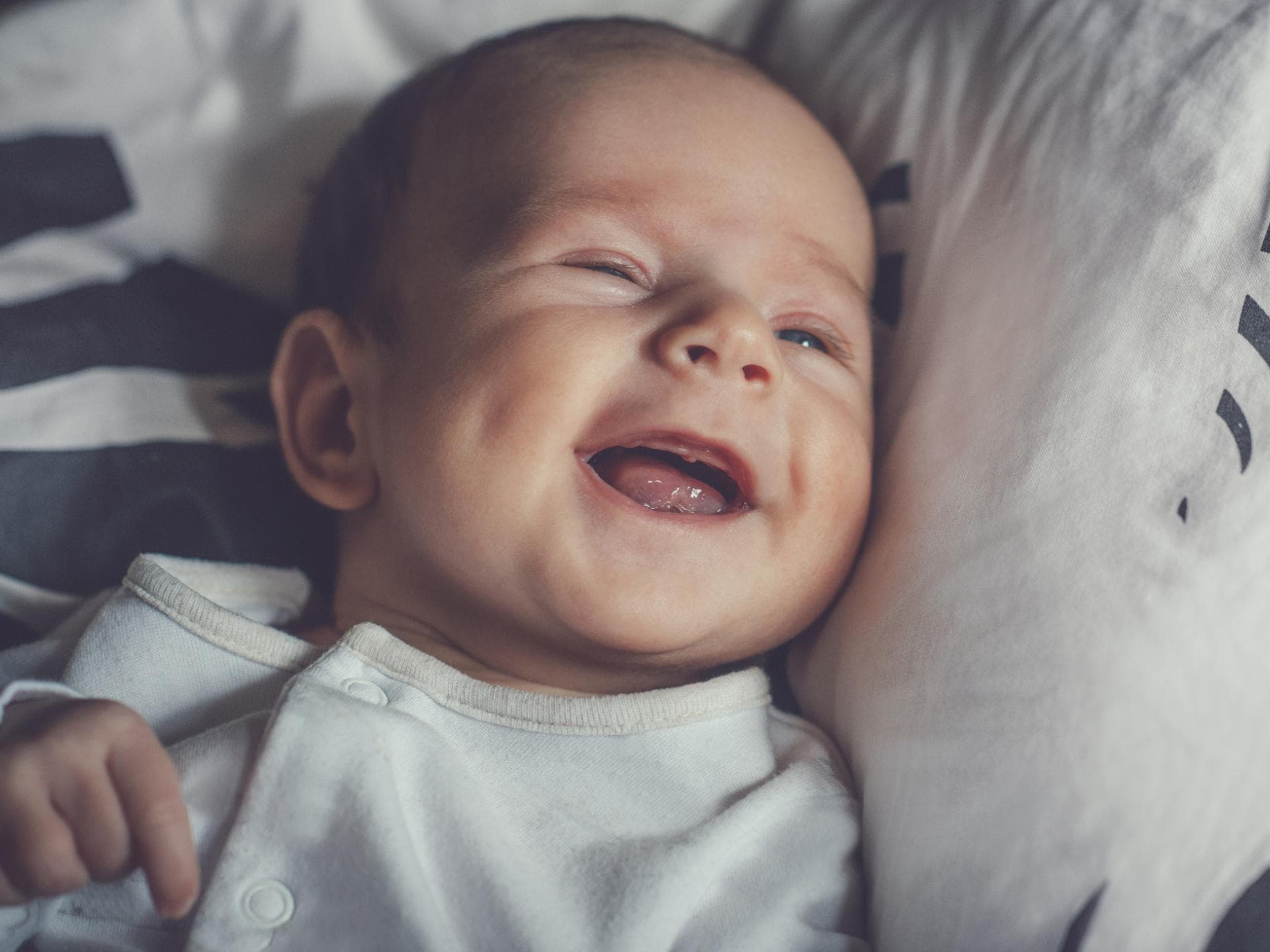 Kleiner Baby-Junge lacht zufrieden und liegt auf dem Bett. Kleiner Baby-Junge lacht zufrieden und liegt auf dem Bett.