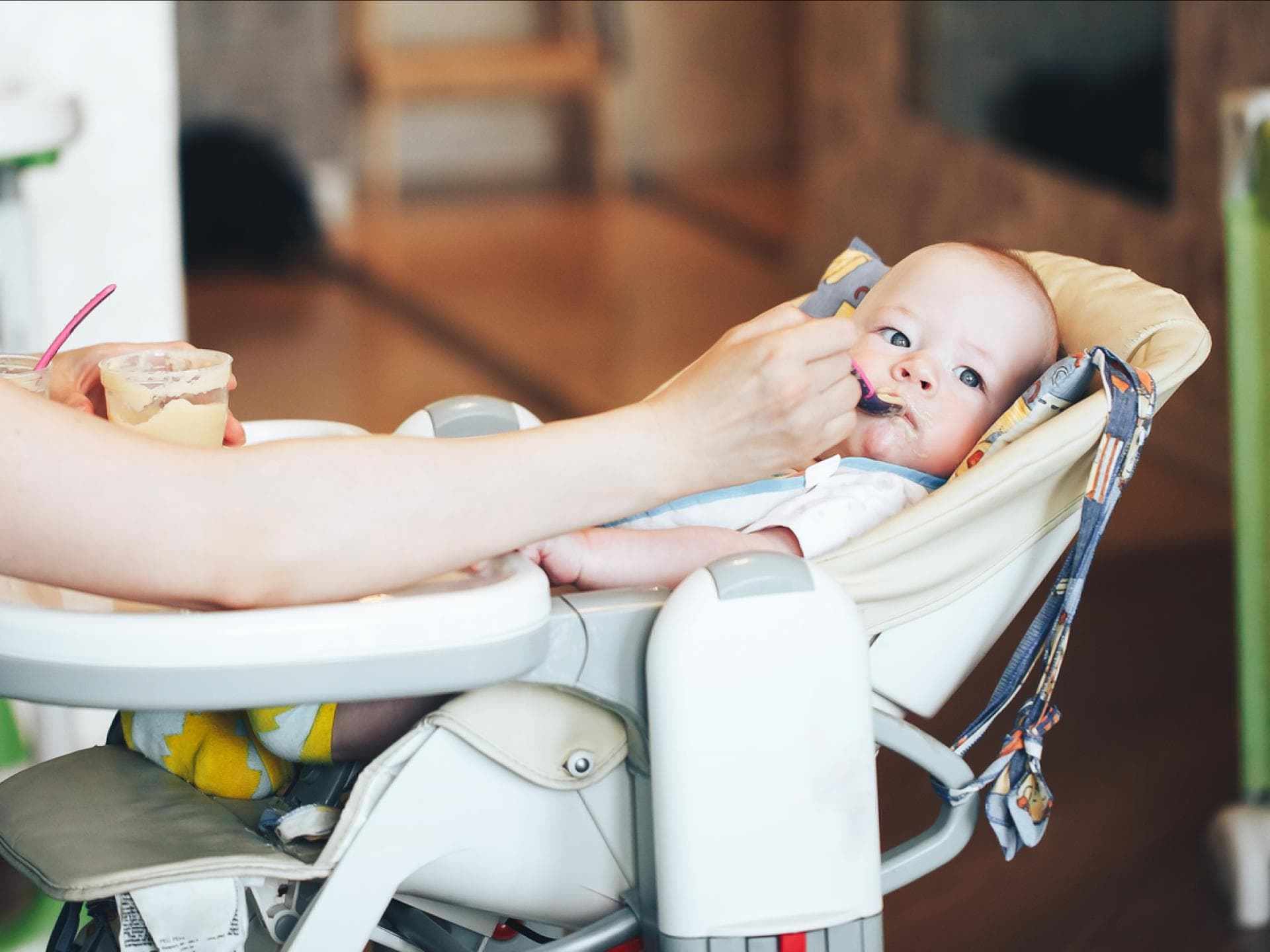 Baby liegt und isst im Hochstuhl