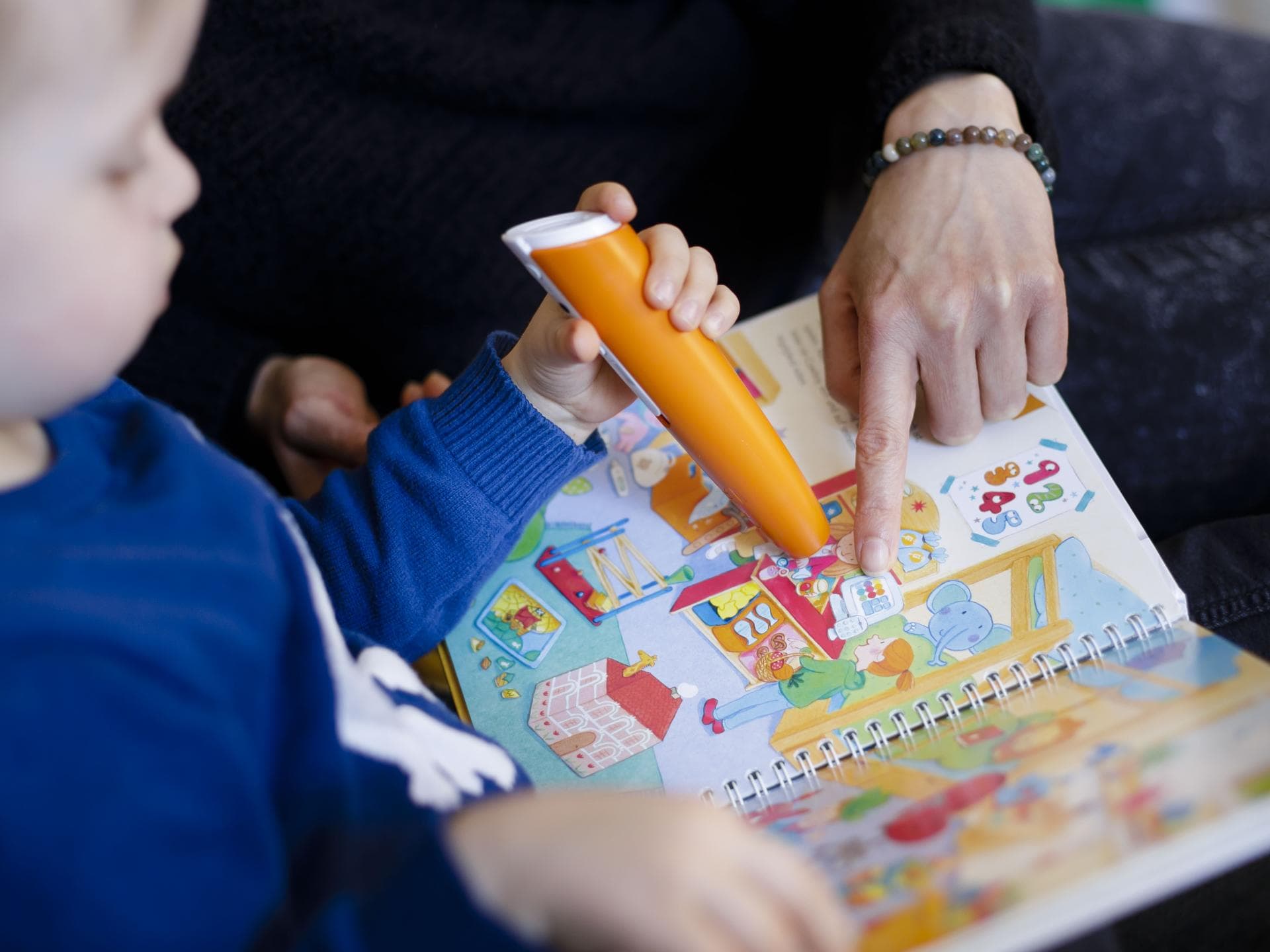 Ein kleiner Junge schaut gemeinsam mit einer Frau ein Tiptoi-Kinderbuch an. Ein kleiner Junge schaut gemeinsam mit einer Frau ein Tiptoi-Kinderbuch an.
