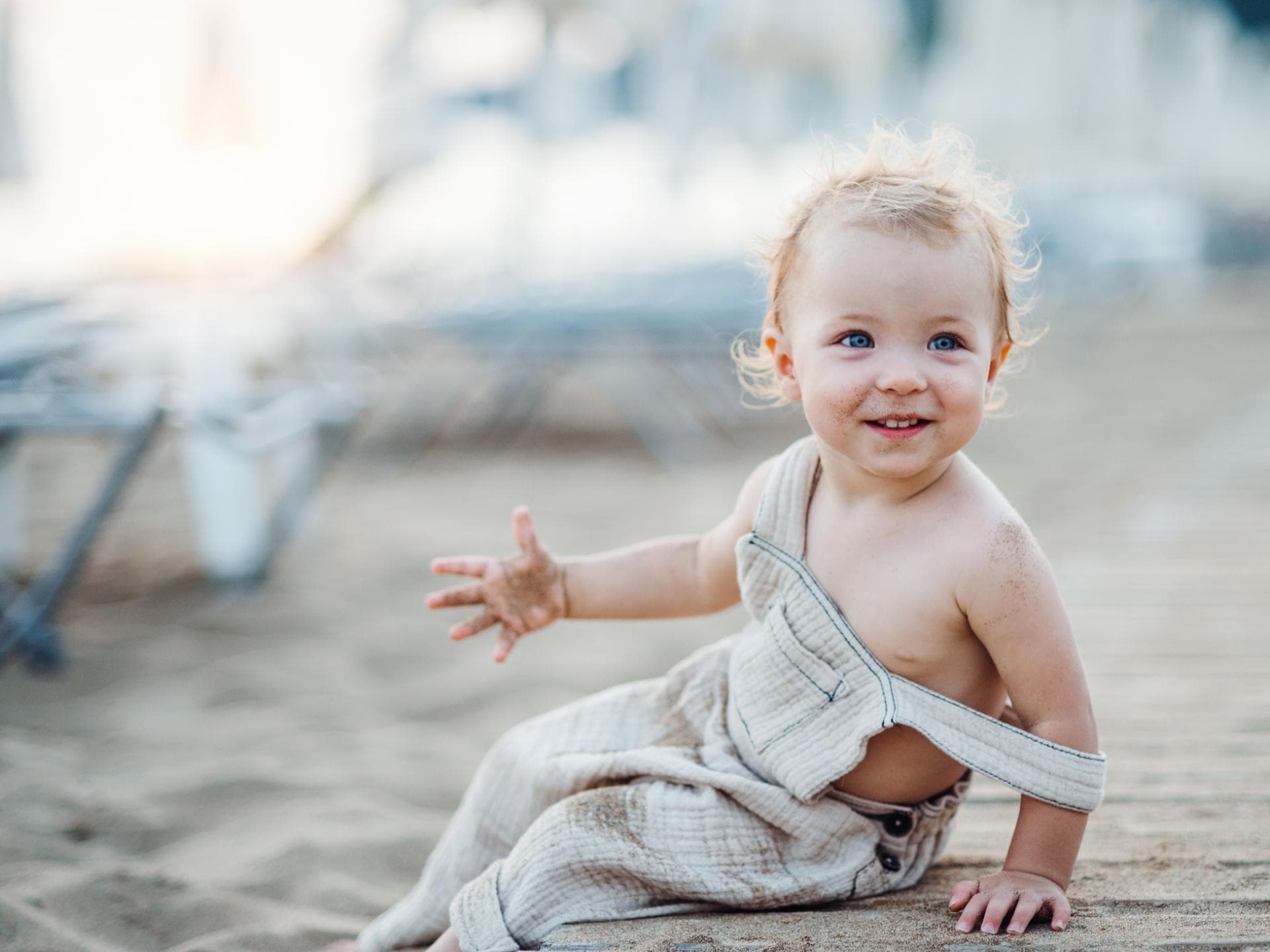 Ein kleines Mädchen sitzt mit Sand an den Händen am Strand. Ein kleines Mädchen sitzt mit Sand an den Händen am Strand.