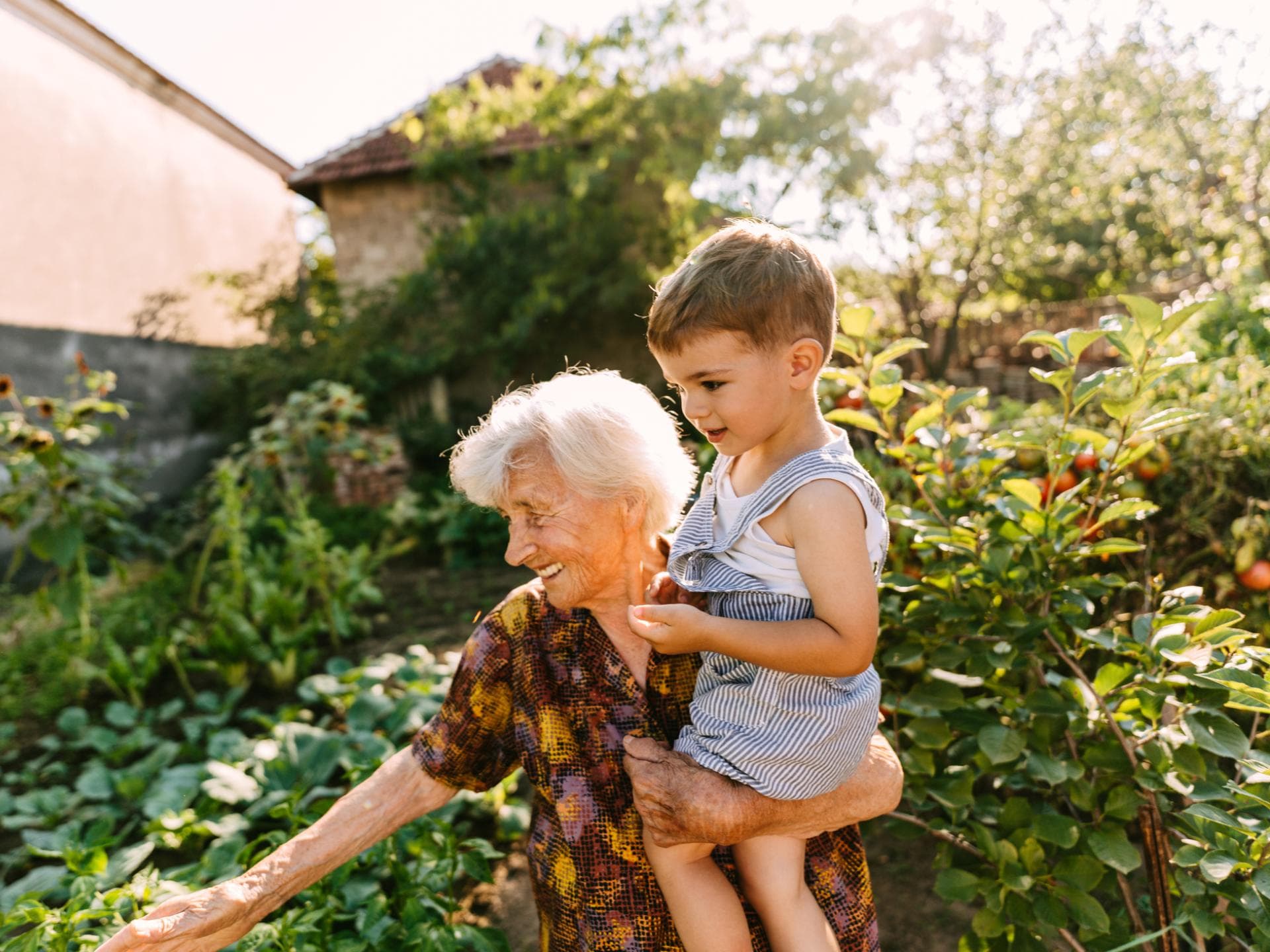 Viele Großeltern vergessen, wie anstrengend das Leben mit Kindern sein kann. Oma mit Enkel im Garten.