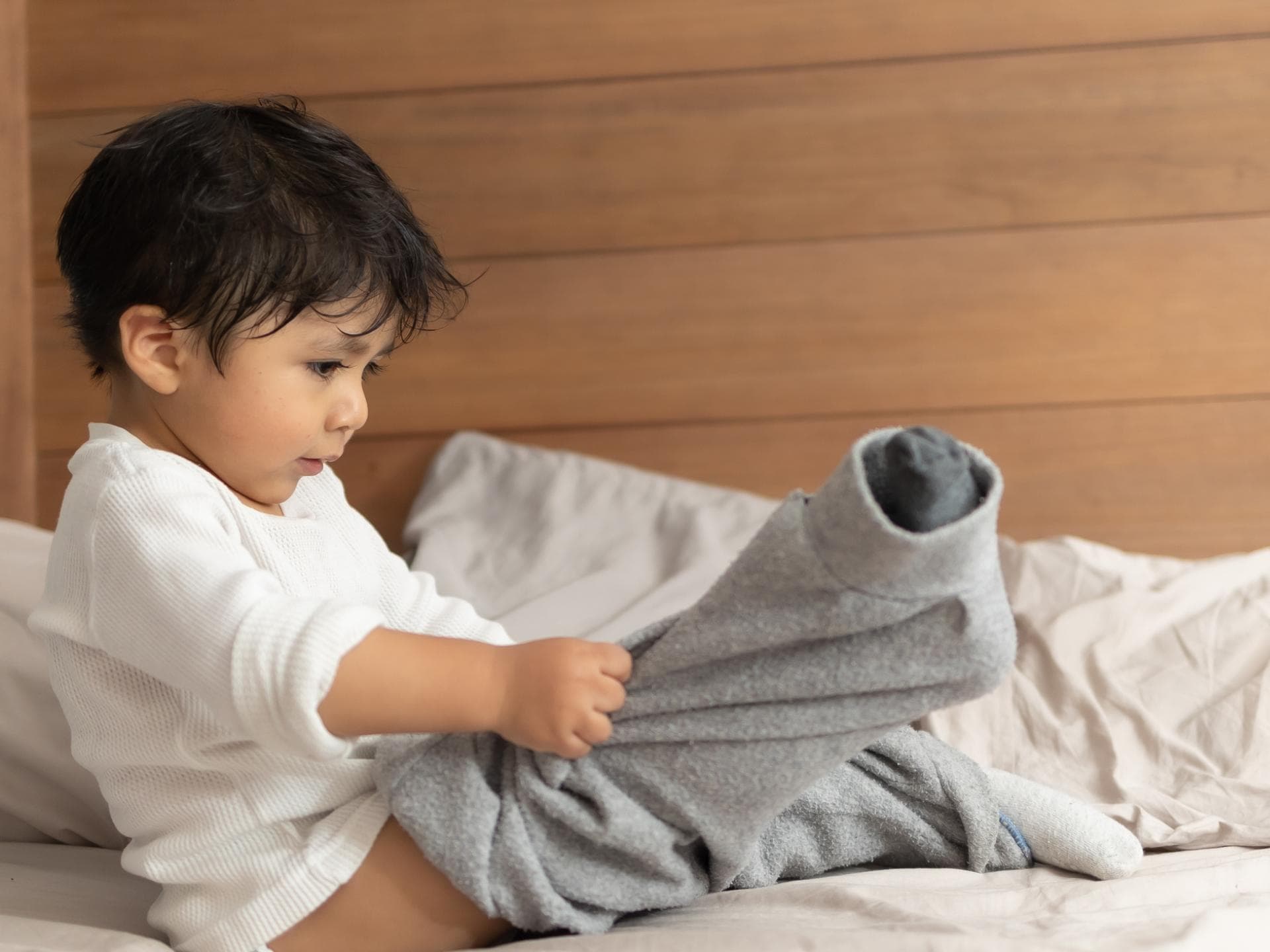 Unpraktische Kleidung für Kinder Ein Kind zieht sich selbst an.
