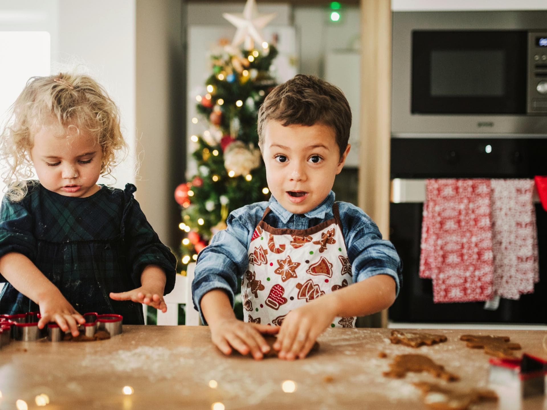 Ein Mädchen und ein Junge kneten zuckerfreien Plätzchen-Teig mit den Händen zur Weihnachtszeit.