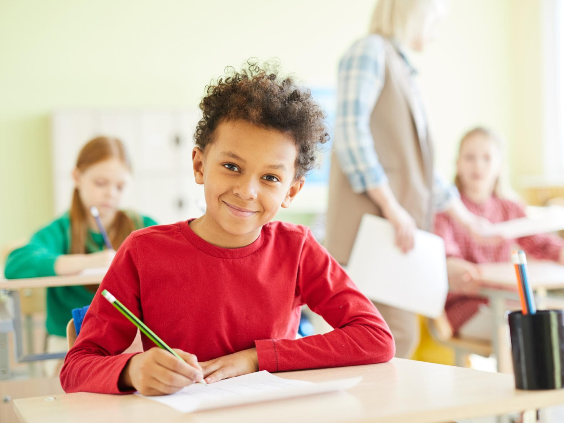 Schüler sitzt lächelnd im Klassenraum.