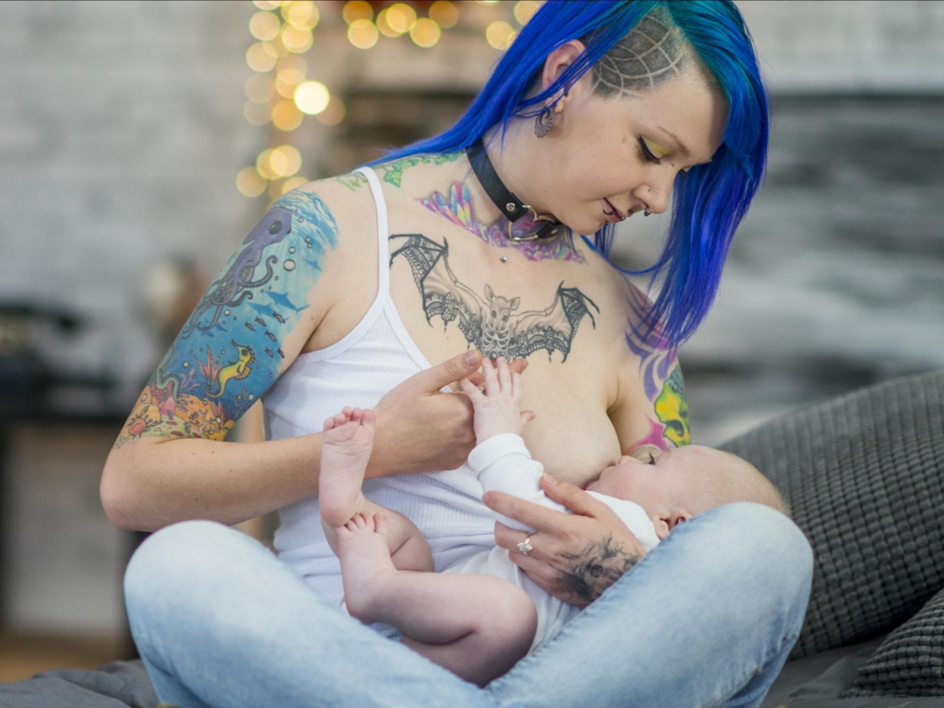 Tätowierte Frau stillt ihr Baby.