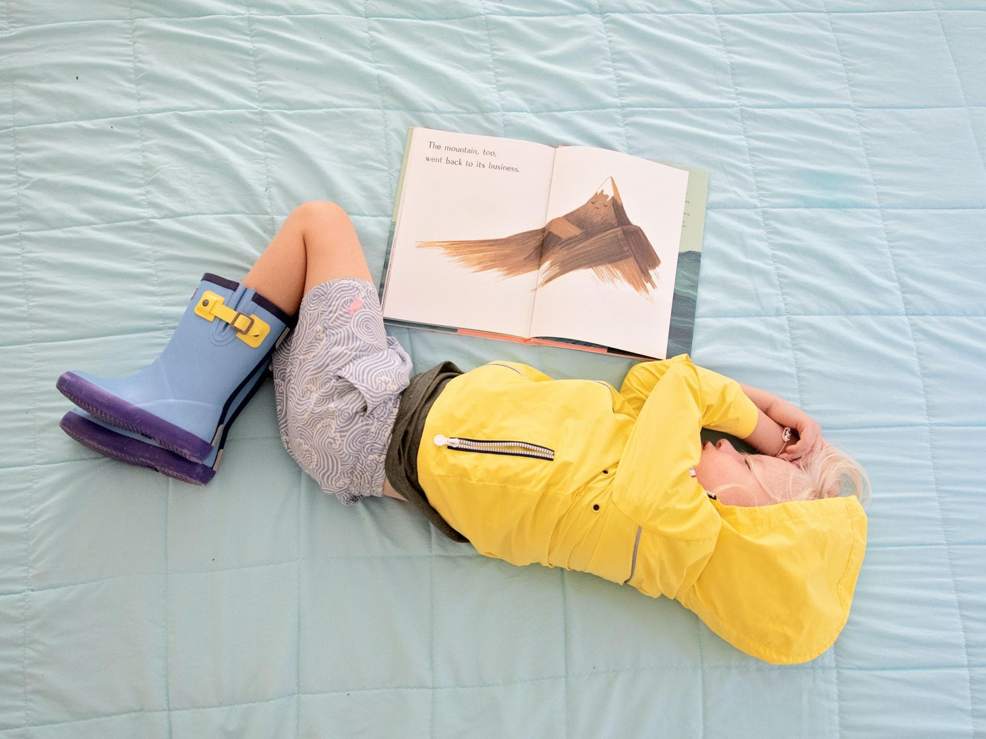 Ein Kind in Regenkleidung beim Lesen eingeschlafen