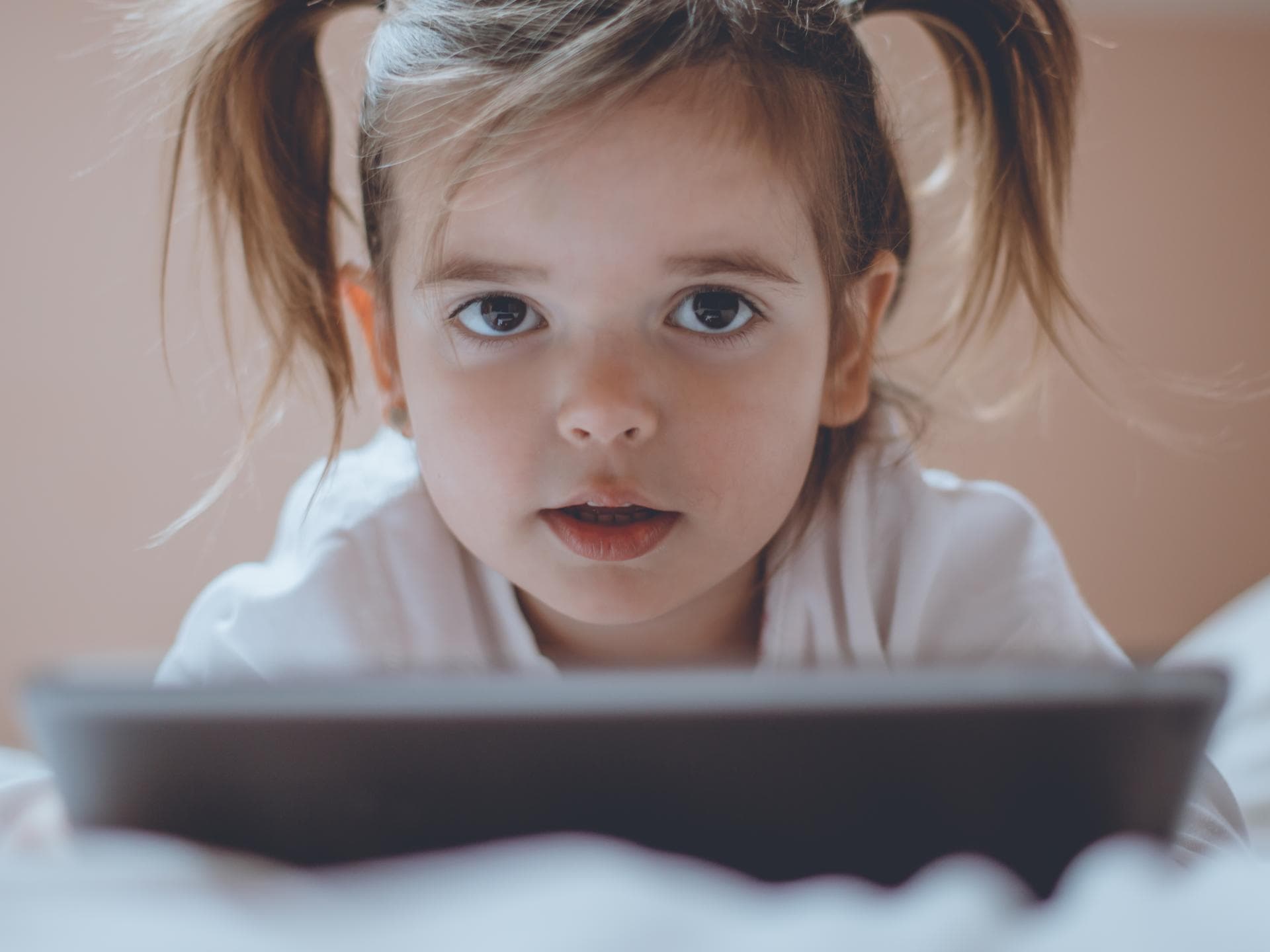 Kleines Mädchen mit Tablet im Bett.
