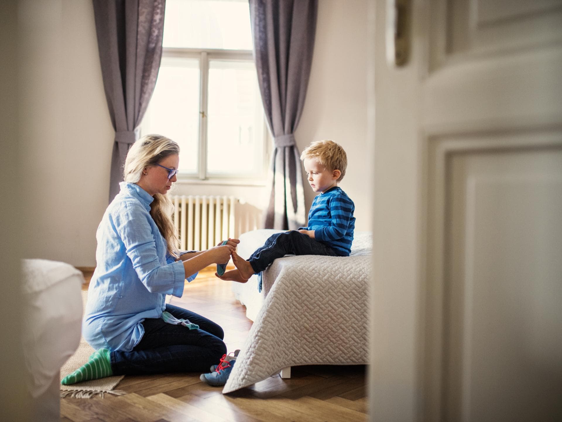 Mutter zieht ihrem Sohn die Socken an.